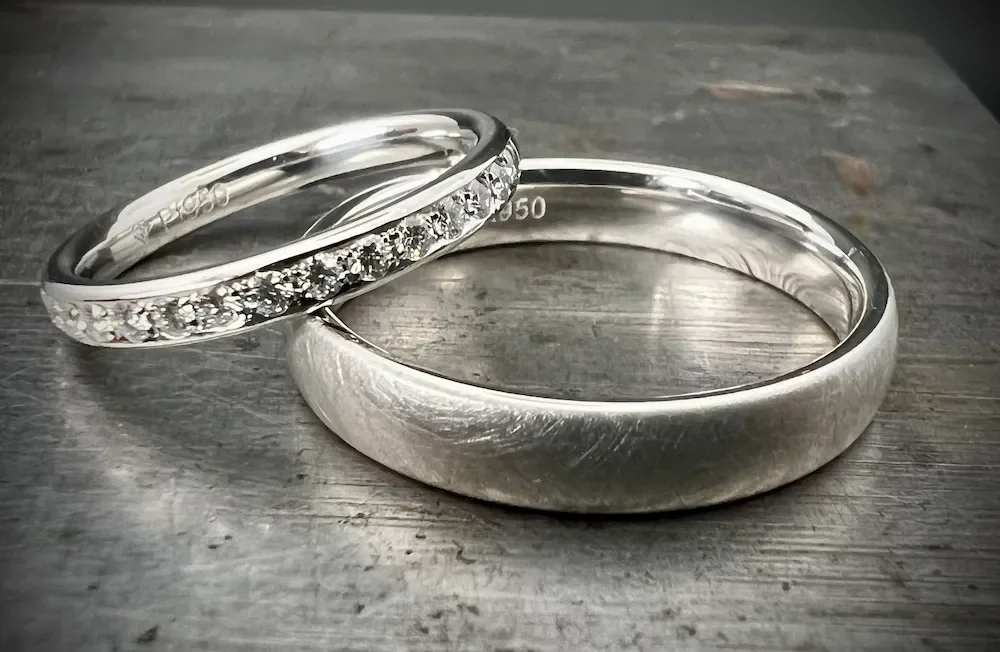 Zwei Silberschmuckringe, einer mit Diamanten und der andere ohne, auf einer Holzoberfläche