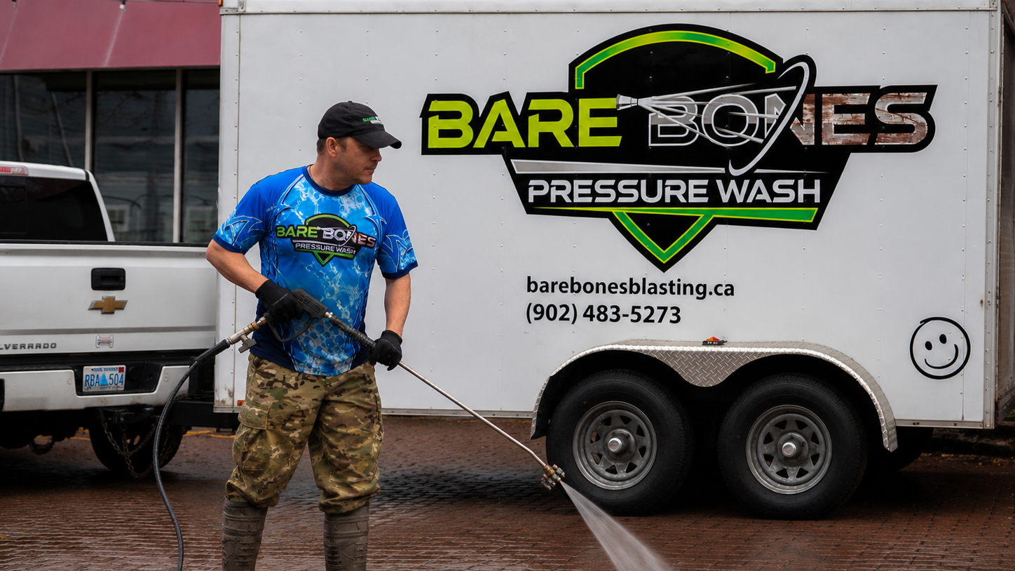 Peter from Bare Bones Blasting washing city sidewalks standing in front of the Bare Bones Truck and Trailer
