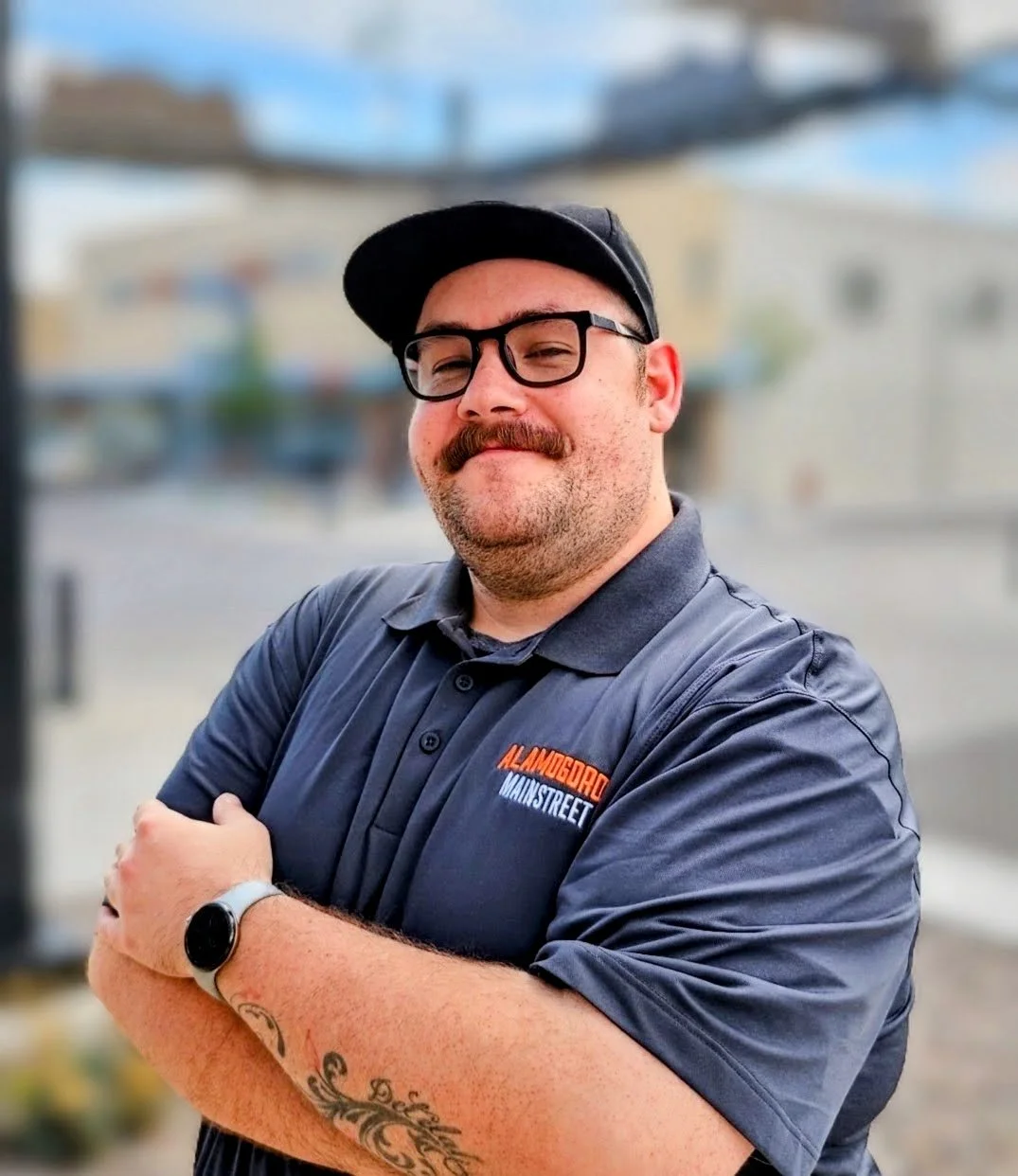 Image of a handsome executive director with hats, mustache, and glasses standing in front of a blurred background