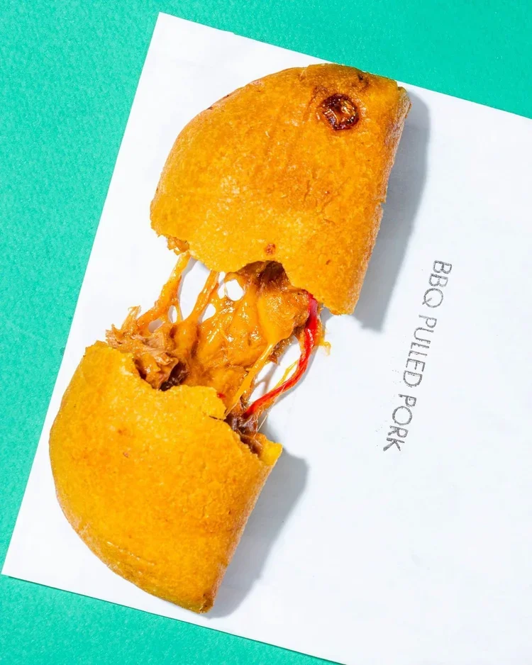 BBQ pulled pork empanada from Empanada Mama torn open to show melted cheese and tender shredded pork.