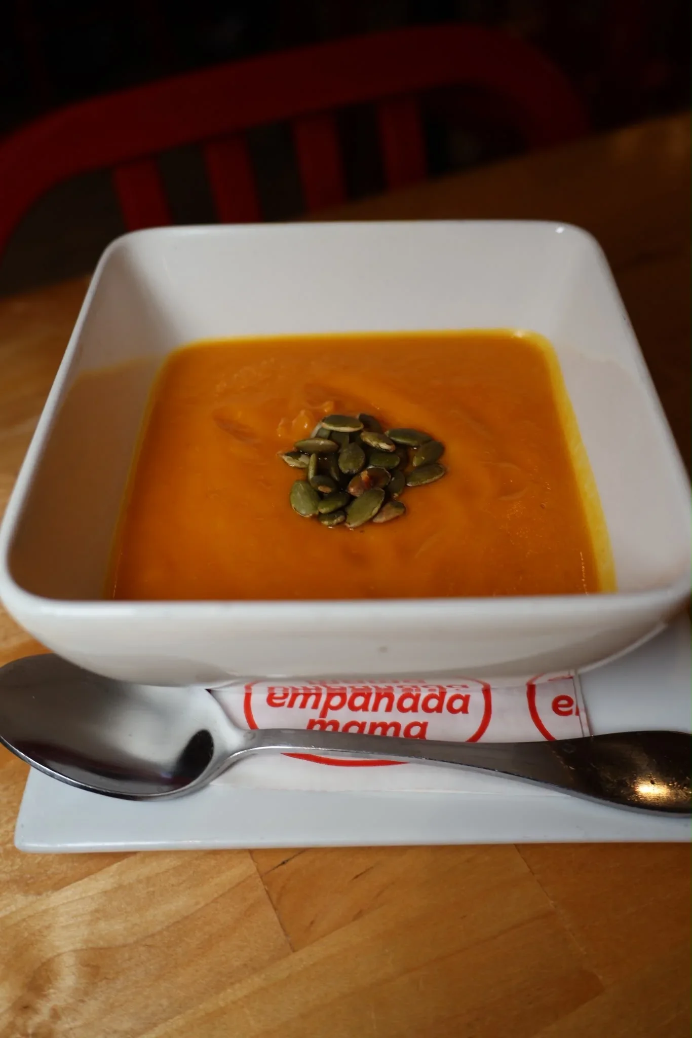 Creamy butternut squash soup topped with toasted pumpkin seeds, served as a seasonal fall special at Empanada Mama.