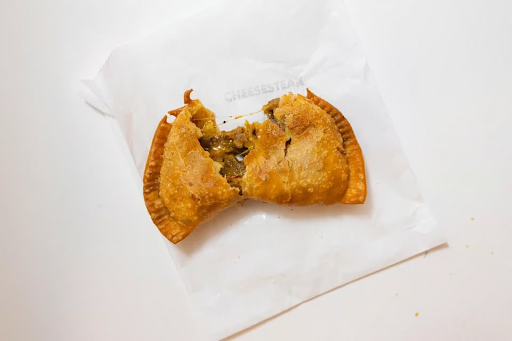 Close-up of a hot Cheesesteak Empanada by Empanada Mama with melted cheese oozing out, perfect for late-night bites.