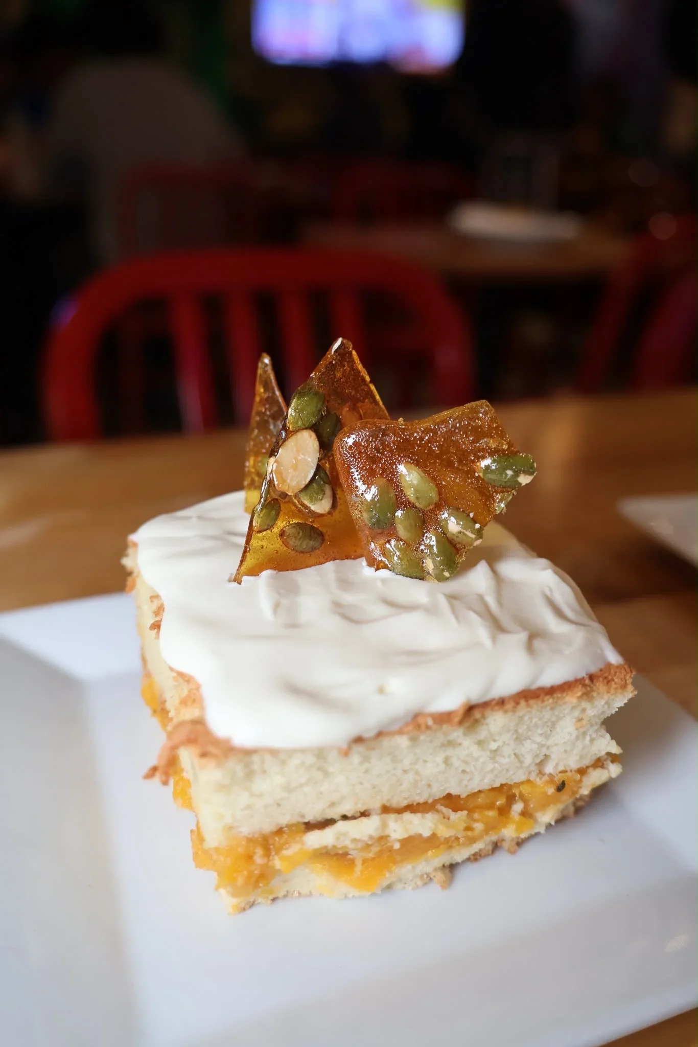 Rum-Kissed Butternut Tres Leches cake topped with pumpkin cream, toasted pumpkin seeds, and praline.