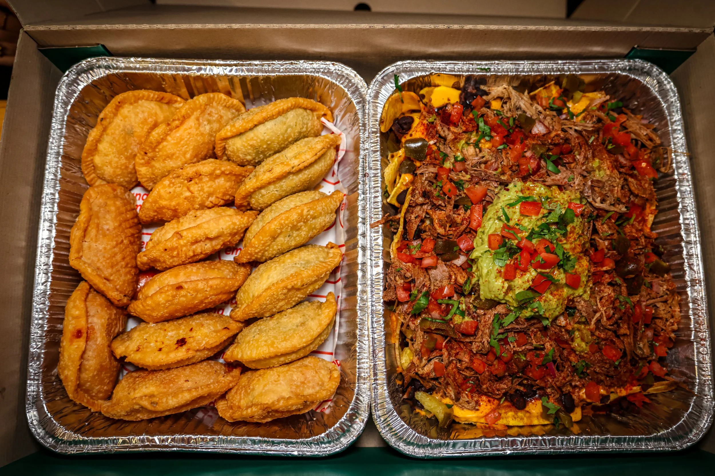 Empanadas served with loaded nachos topped with shredded meat, guacamole, salsa, and fresh toppings.