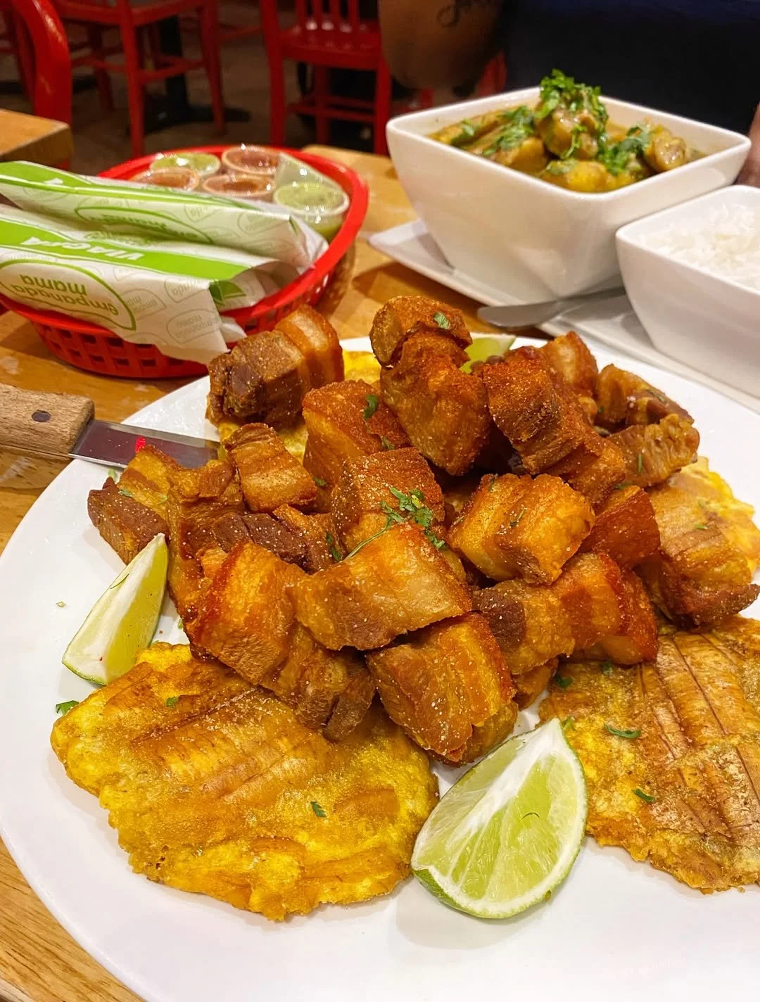 Chicharrón platter with lime wedges and Colombian sides served at Empanada Mama.