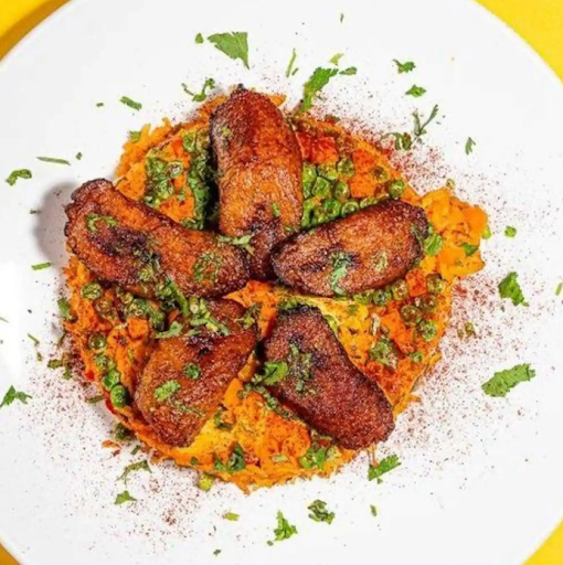 Colombian-style arroz con pollo from Empanada Mama served with seasoned rice, chicken, and fresh sides.