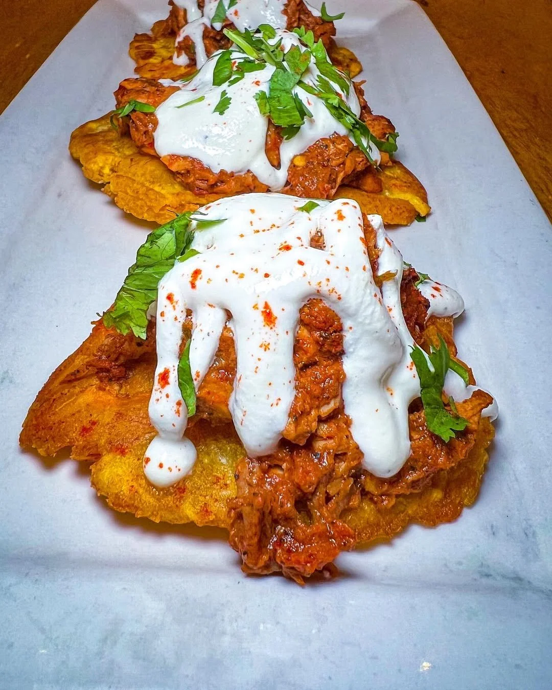 Spicy chicken tostones topped with white sauce served at Empanada Mama.