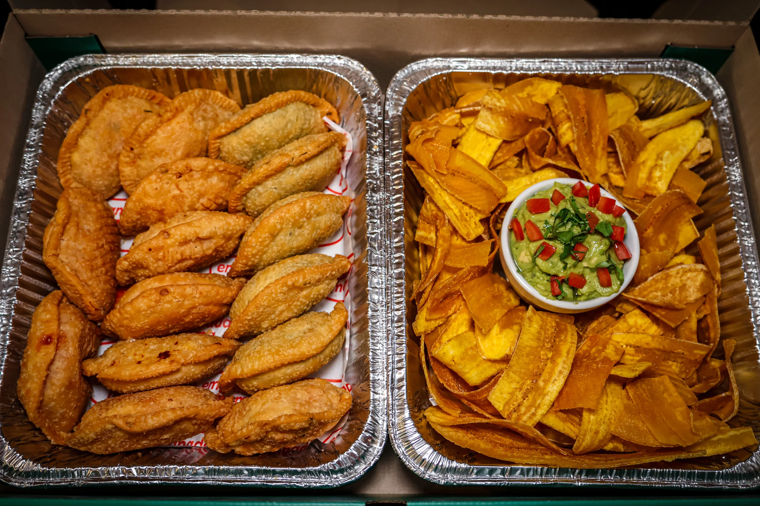 Golden empanadas and crispy plantain chips served with a side of fresh guacamole.