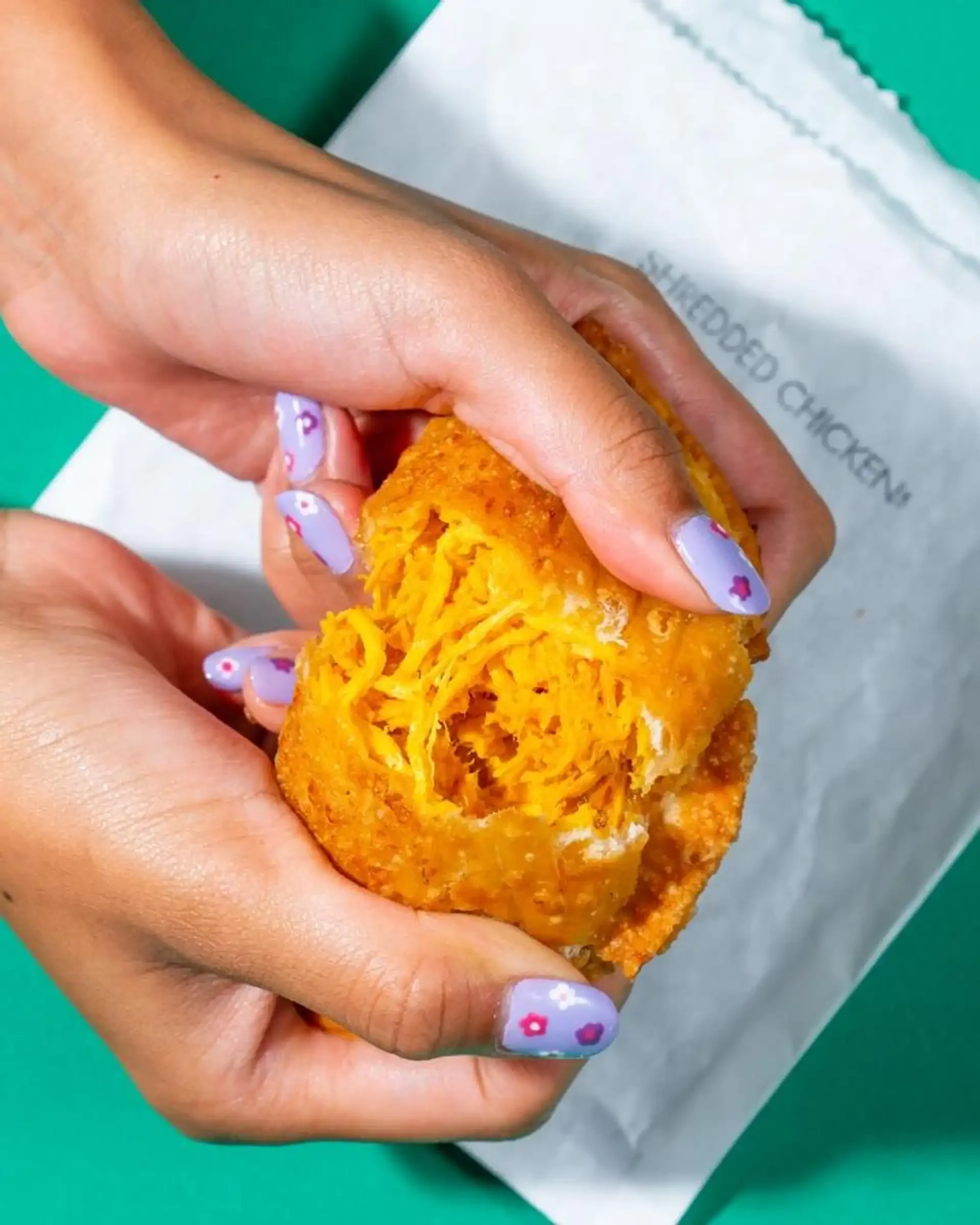 Shredded chicken empanada from Empanada Mama, golden crust cut open to show juicy filling.