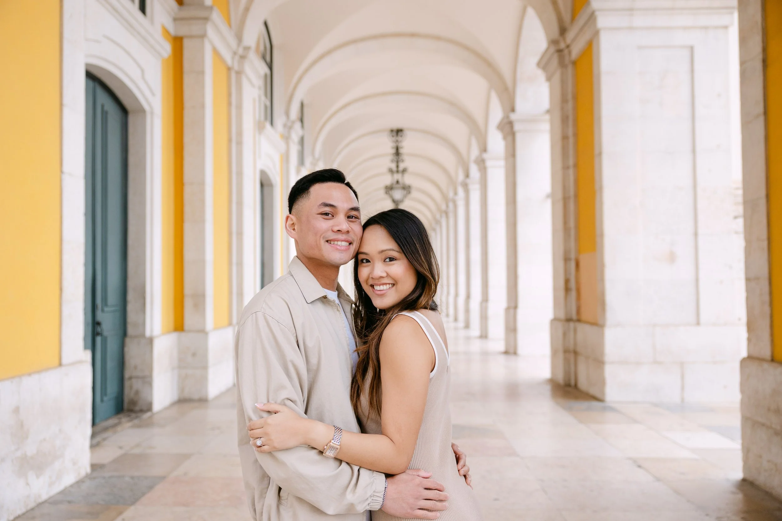 Engaged couple posing together under arches at Terreiro do Paço in Lisbon