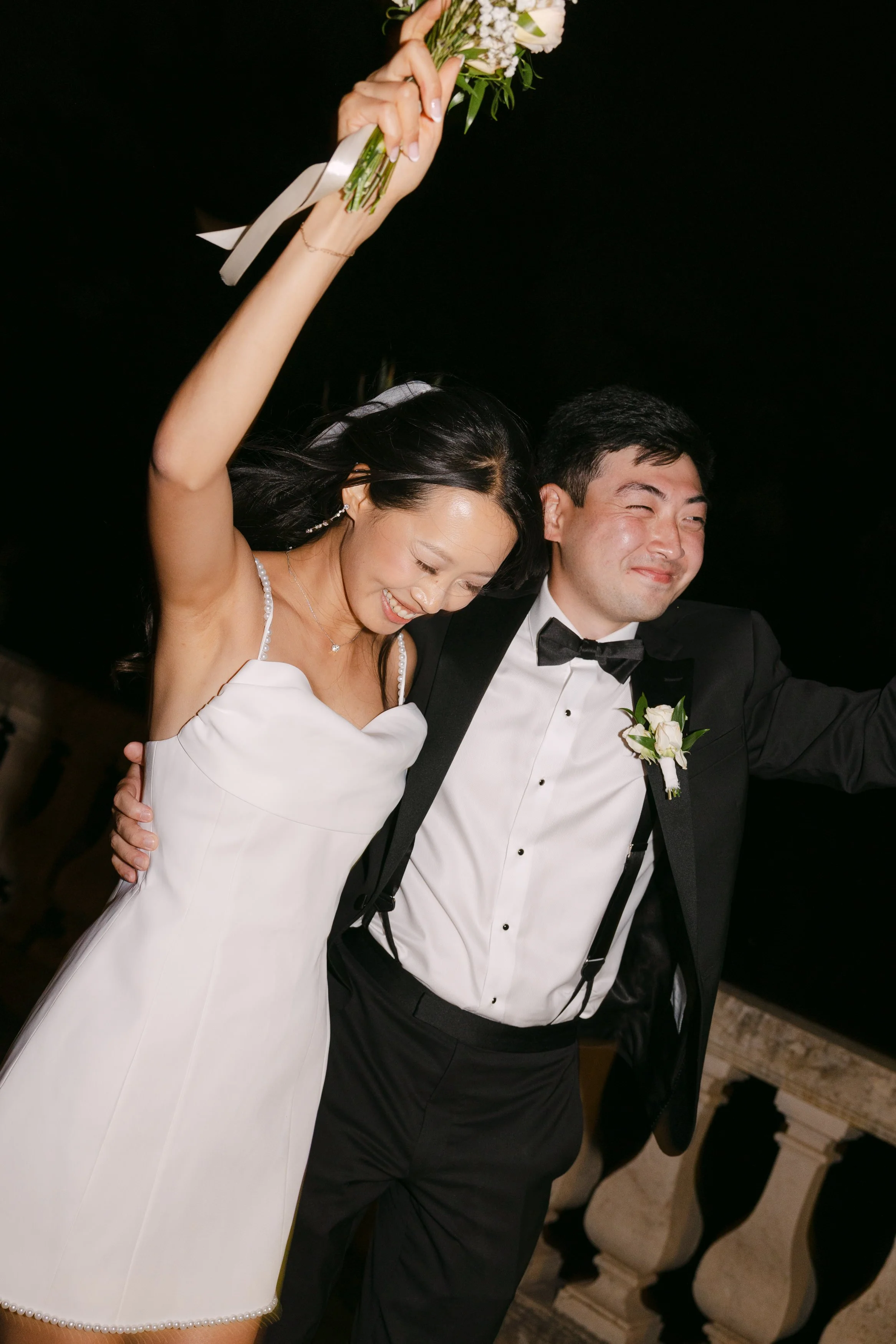 Newlyweds celebrating together on the dance floor as the bride raises her bouquet in the air at Palácio Nacional de Queluz.
