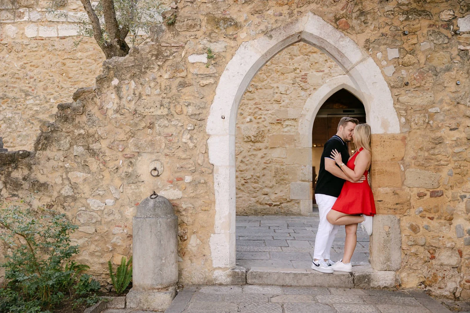 Engagement photos in a historic archway at Castelo de São Jorge in Lisbon