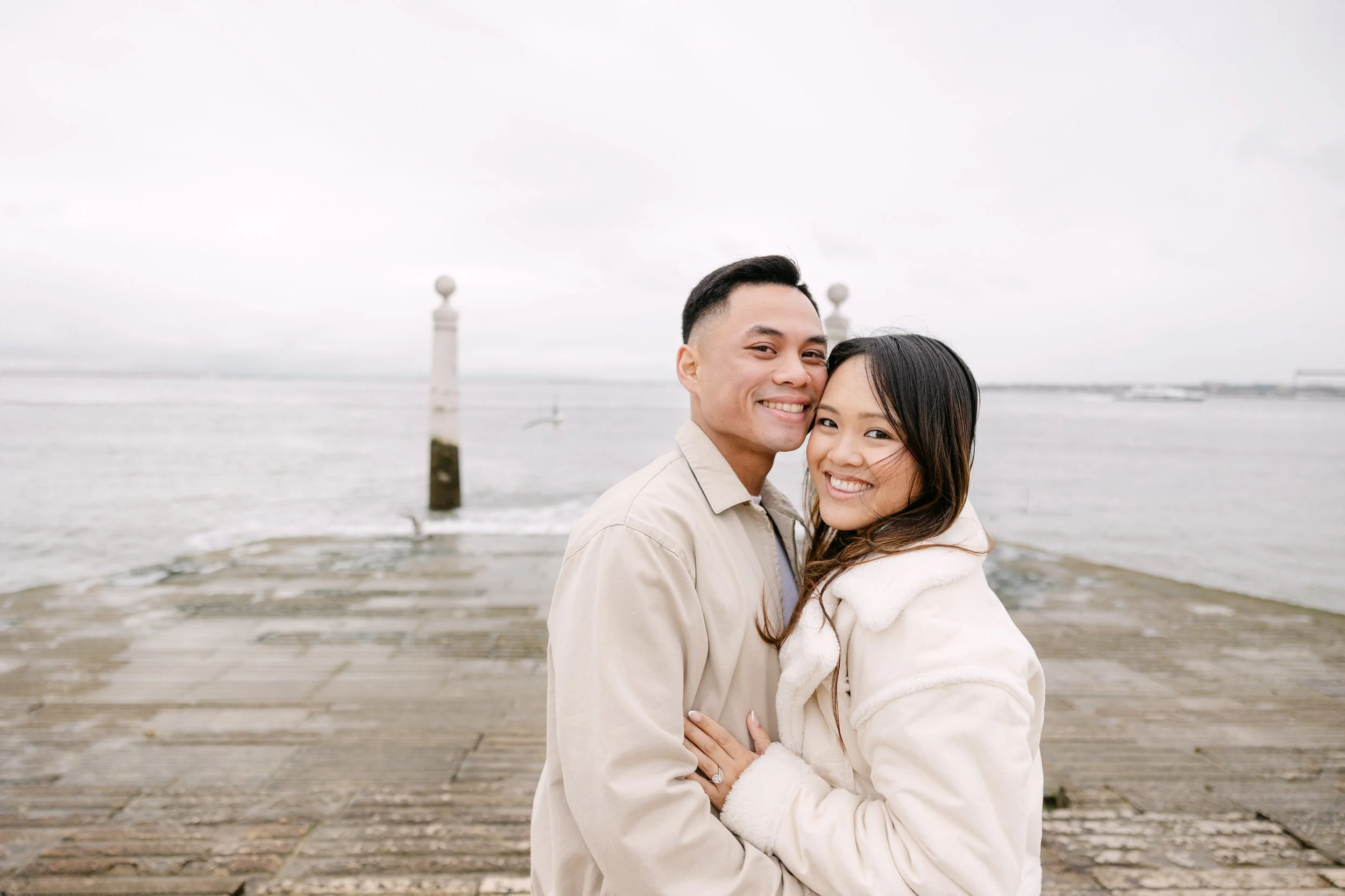 Portrait of recently engaged couple smiling together by the river at Cais das Colunas in Lisbon