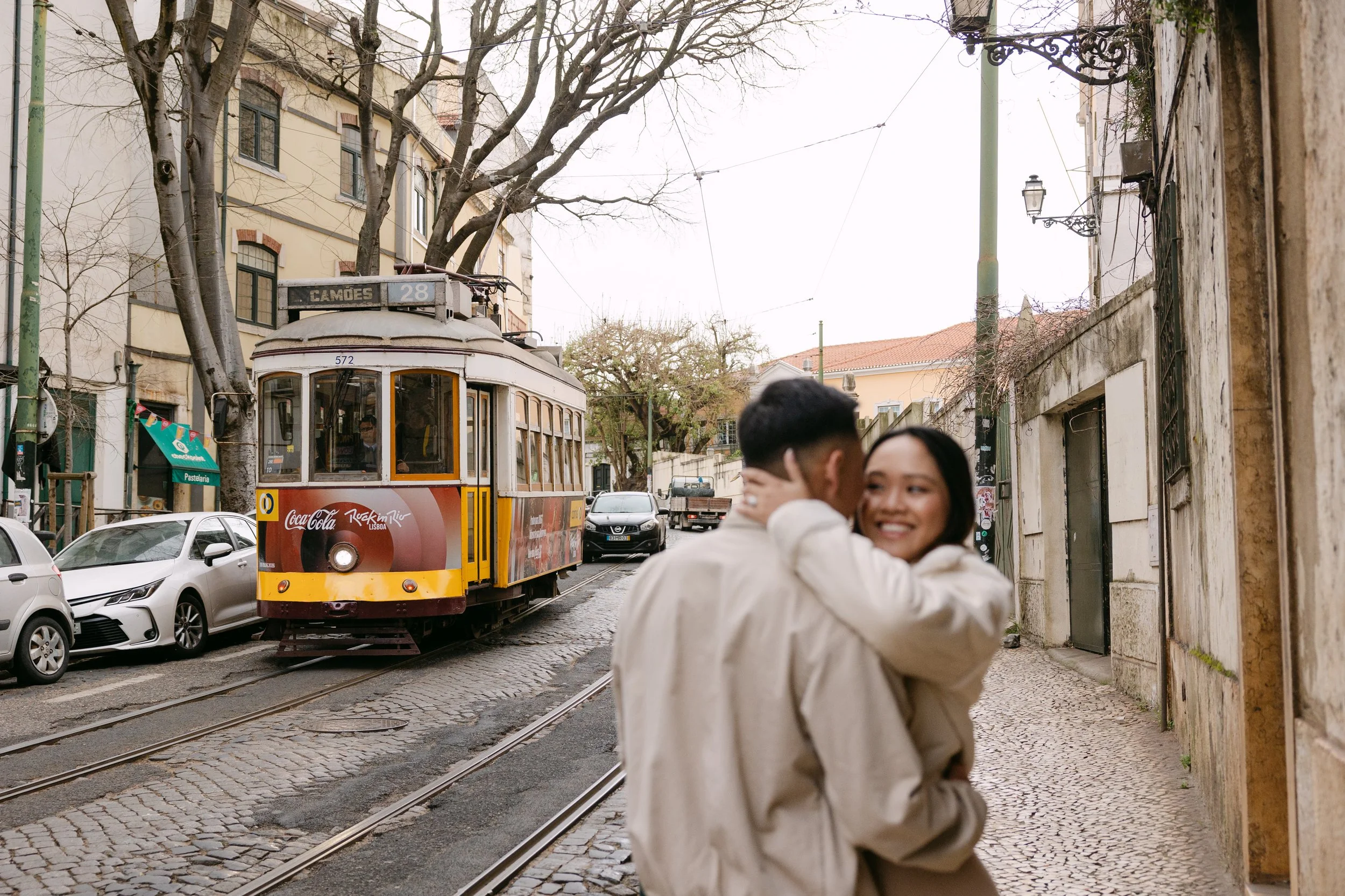 Couple embracing near iconic yellow tram during engagement session in Lisbon