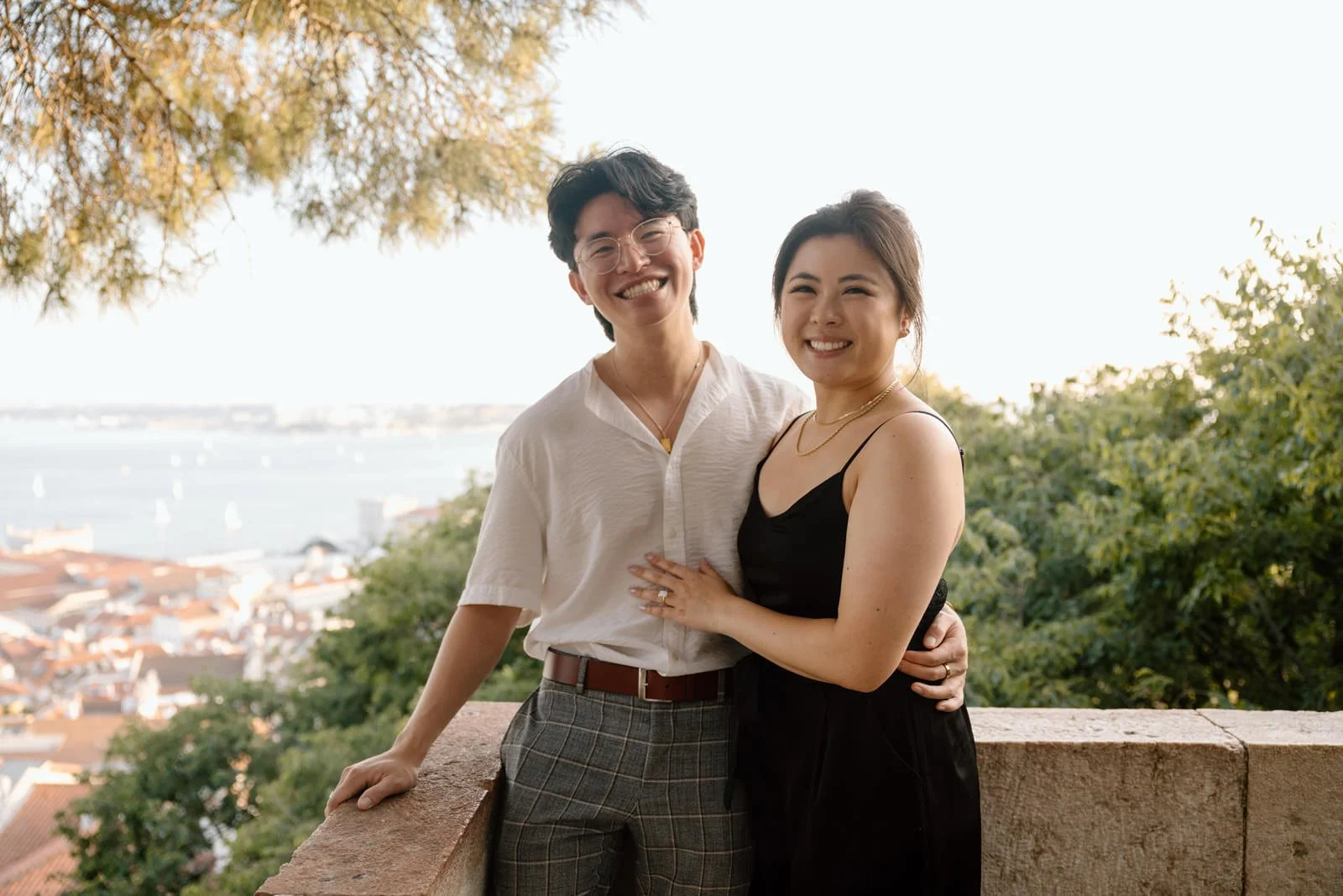 Couple celebrating their engagement with views over Lisbon during a sunset photoshoot at Castelo de São Jorge.
