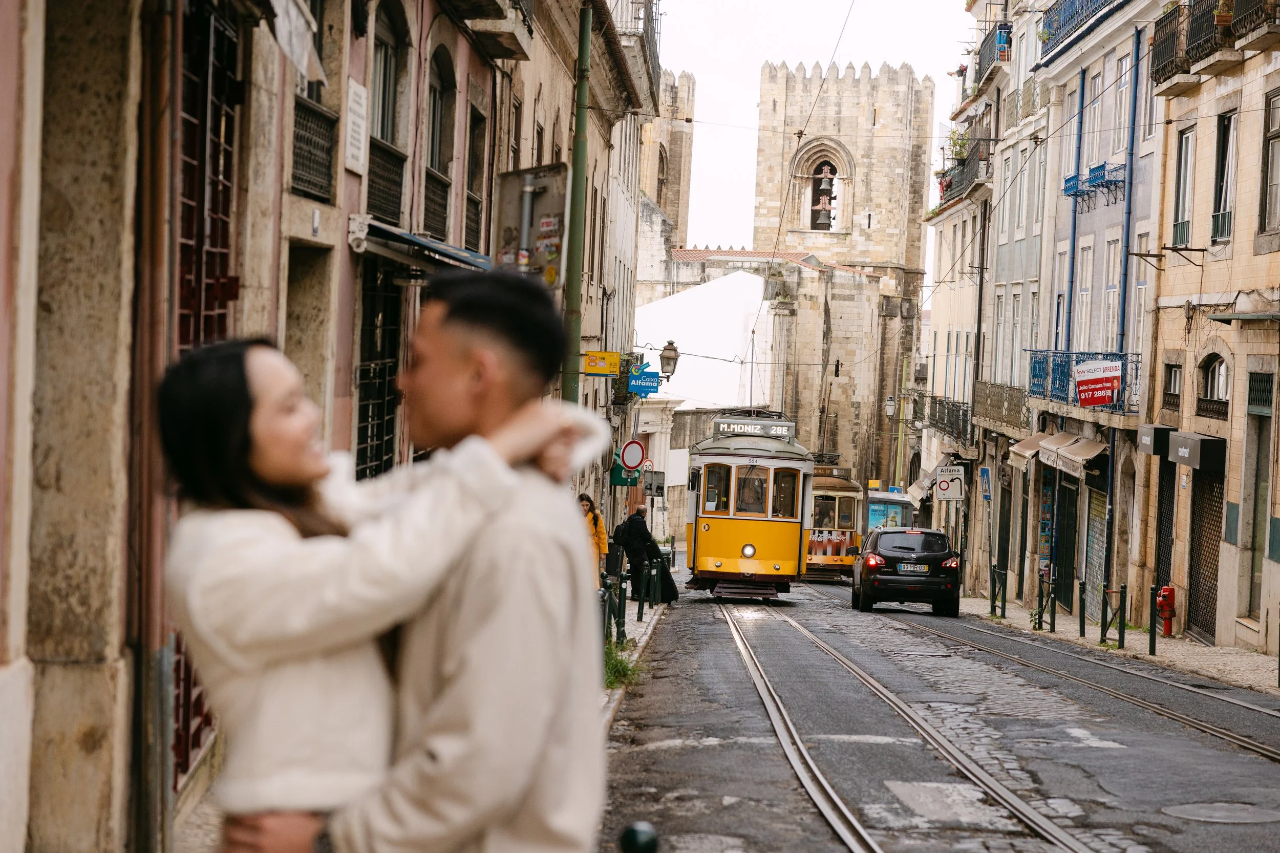 Romantic portrait of engaged couple in Alfama street with Lisbon tram in background