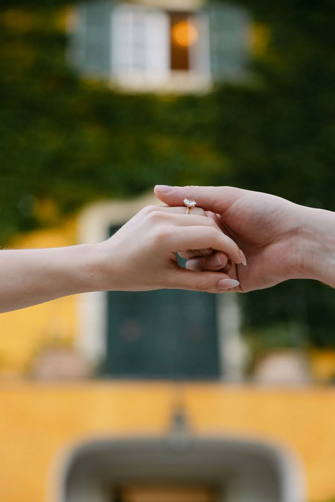 Close-up of a newly engaged couple holding hands with the engagement ring in focus at Quinta de Sant’Ana in Portugal.
