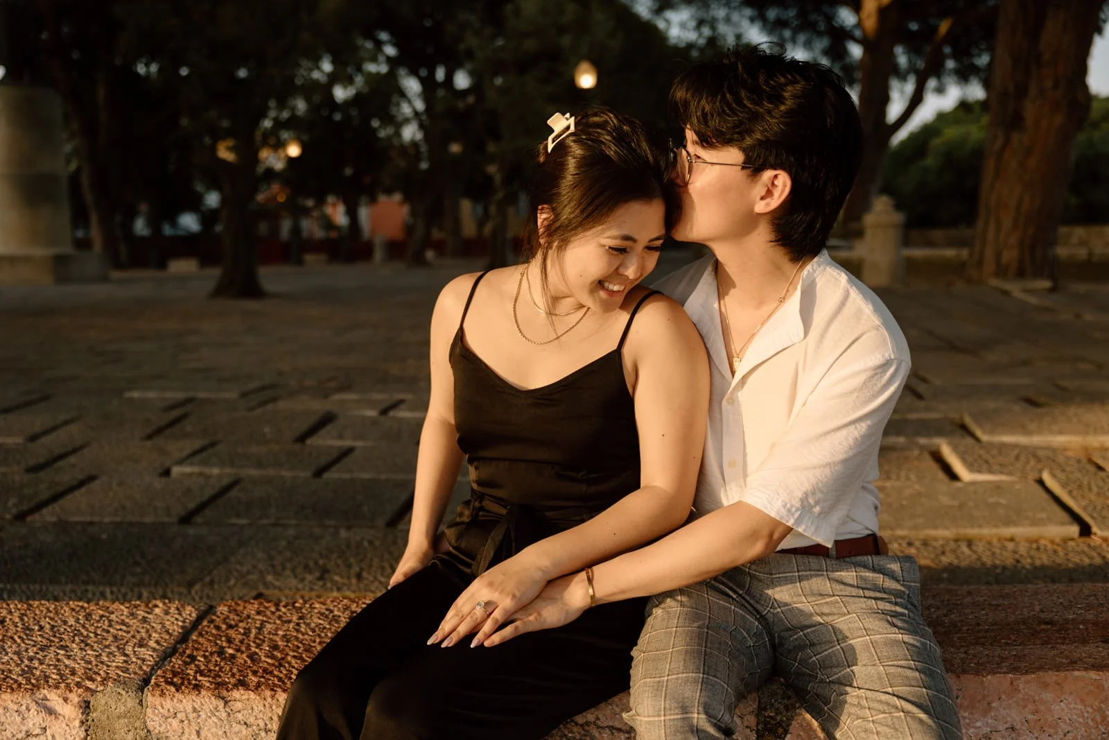 Newly engaged couple enjoying golden hour after a surprise proposal at Castelo de São Jorge in Lisbon.