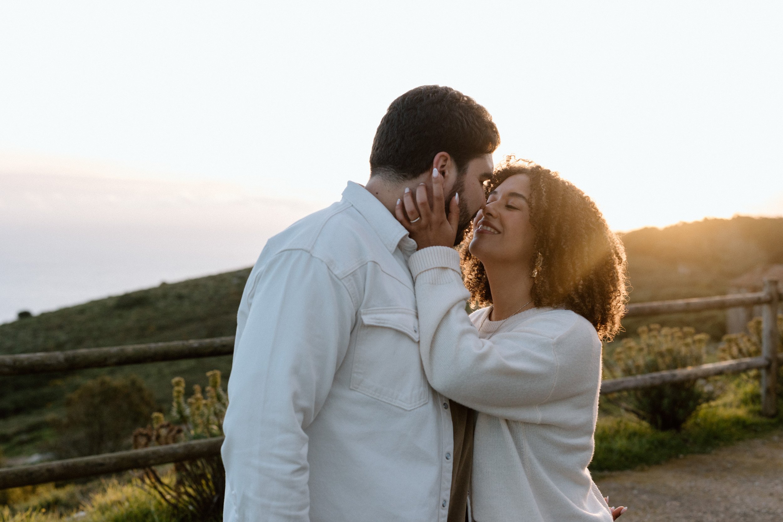 Romantic golden hour portrait of engaged couple at Santuário da Peninha in Portugal