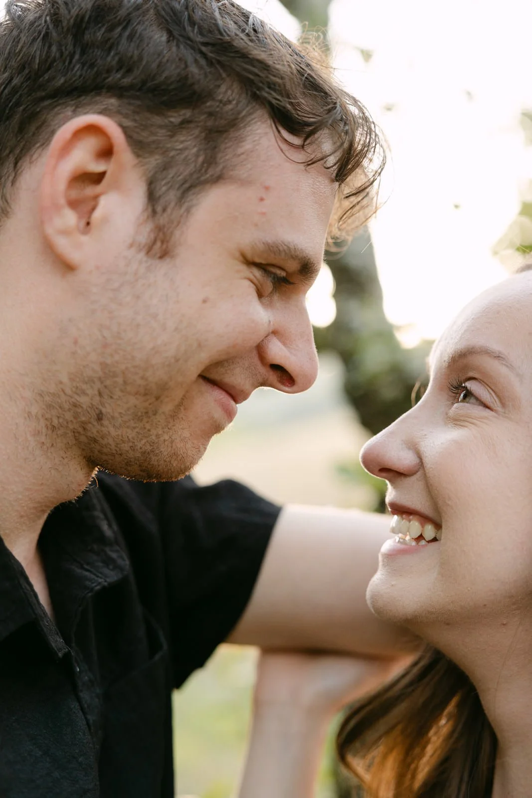 Close-up portrait of a newly engaged couple smiling at each other during their engagement session in the Portuguese countryside.