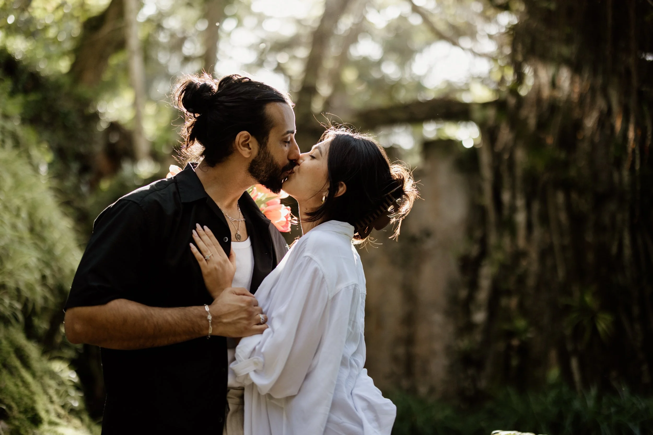 Romantic couple sharing a moment during a forest photoshoot in Sintra, surrounded by towering trees and soft natural light.