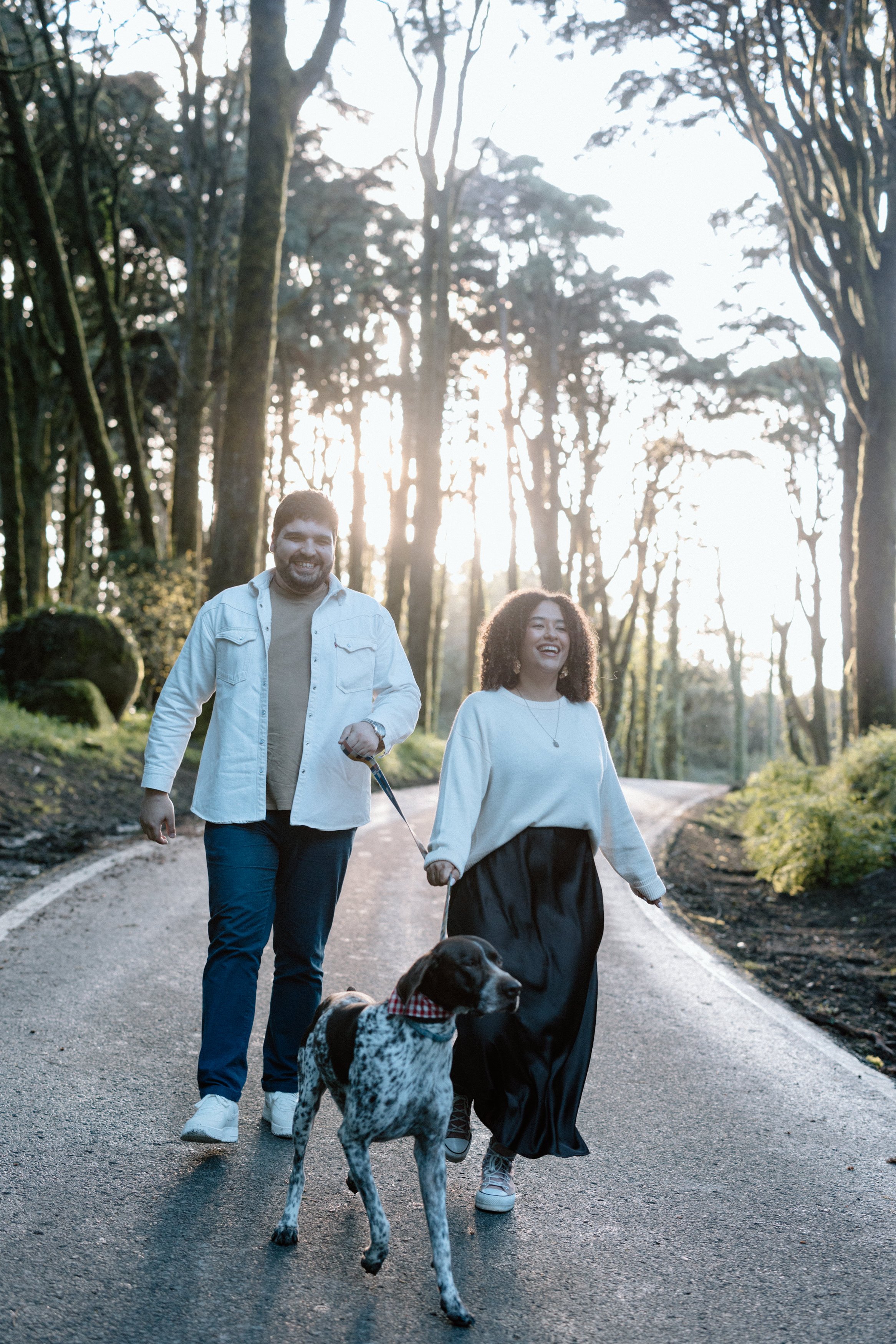 Couple walking together with dog at sunset during engagement session in Sintra