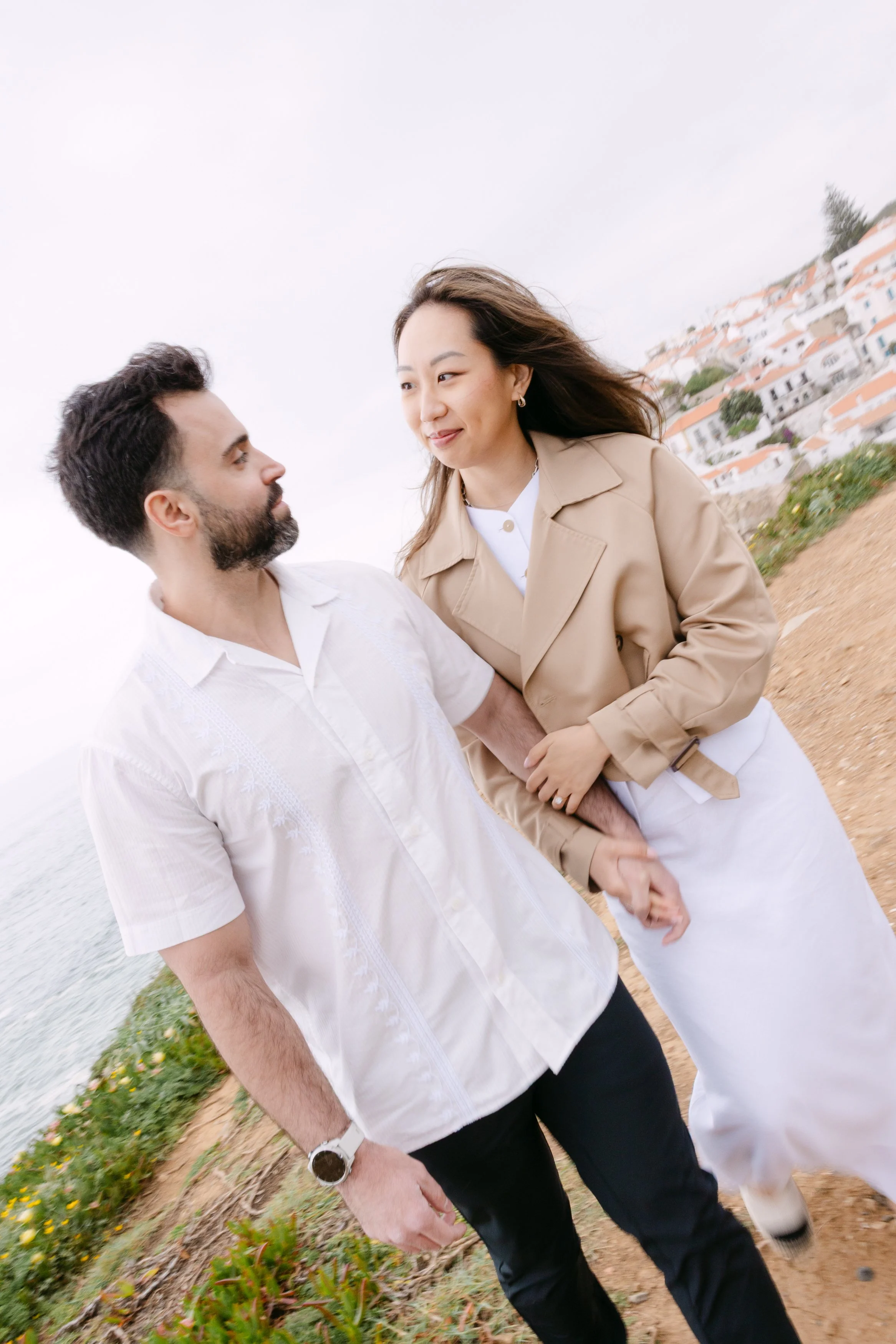Engaged couple walking together along the cliffs of Azenhas do Mar with Atlantic Ocean views.