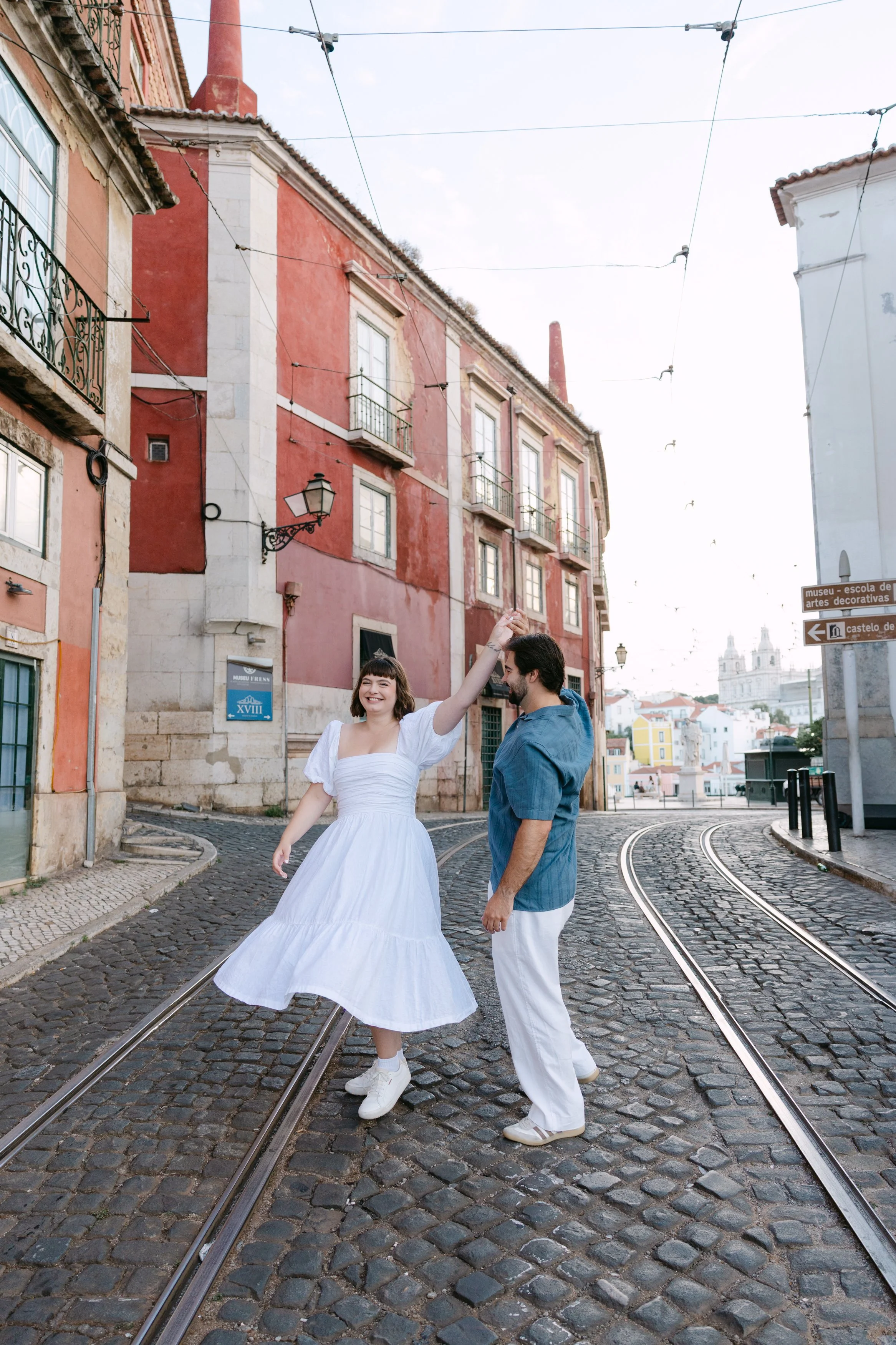Couple laughing and dancing on a cobblestone street during their engagement photos in Alfama, Lisbon.