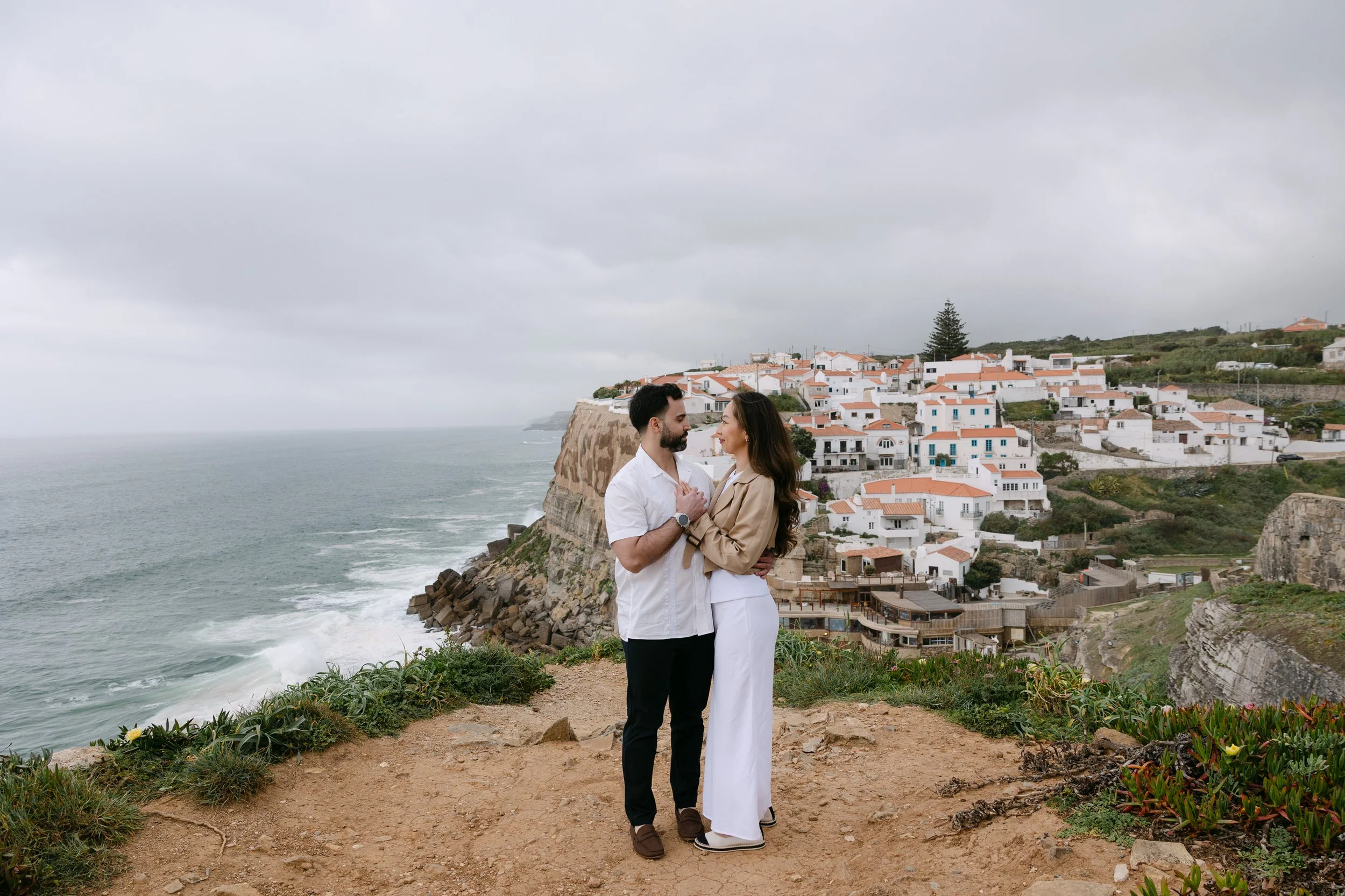 Couple kissing on the cliffs of Azenhas do Mar during coastal engagement photoshoot.