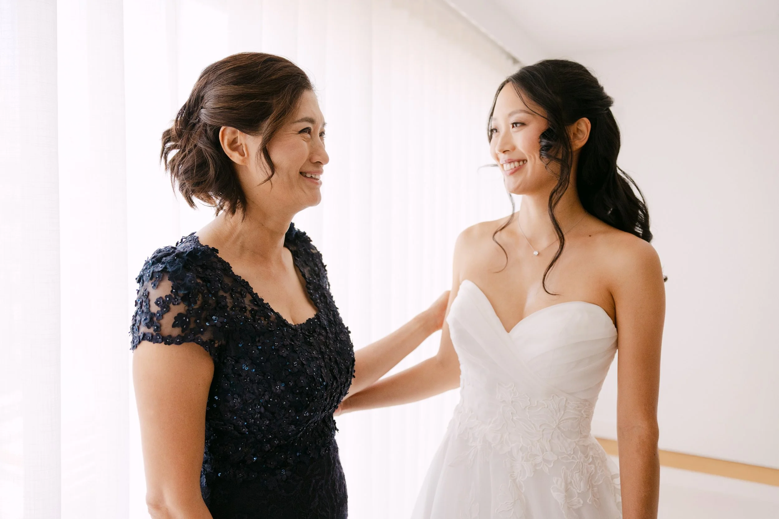 Bride and her mother smiling at each other during an emotional moment together before the wedding ceremony at Palácio Nacional de Queluz.