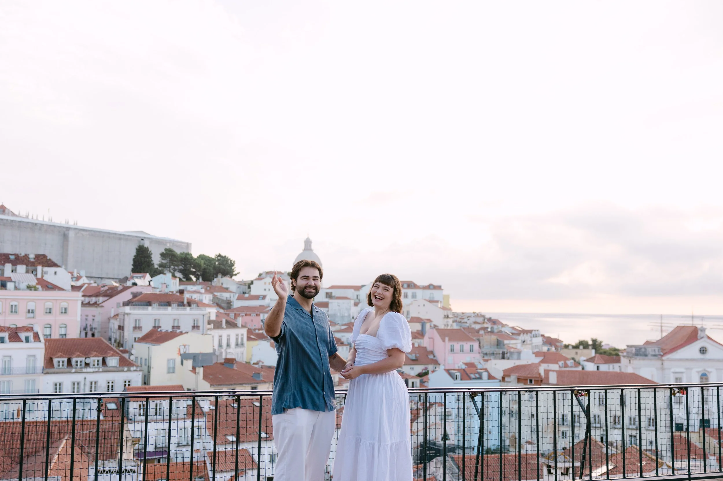 Newly engaged couple celebrating after their sunrise surprise proposal at Portas do Sol in Lisbon.