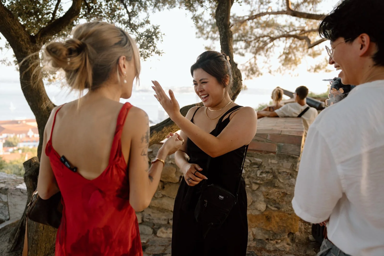 Newly engaged couple celebrating with friends after a surprise proposal at Castelo de São Jorge overlooking Lisbon.