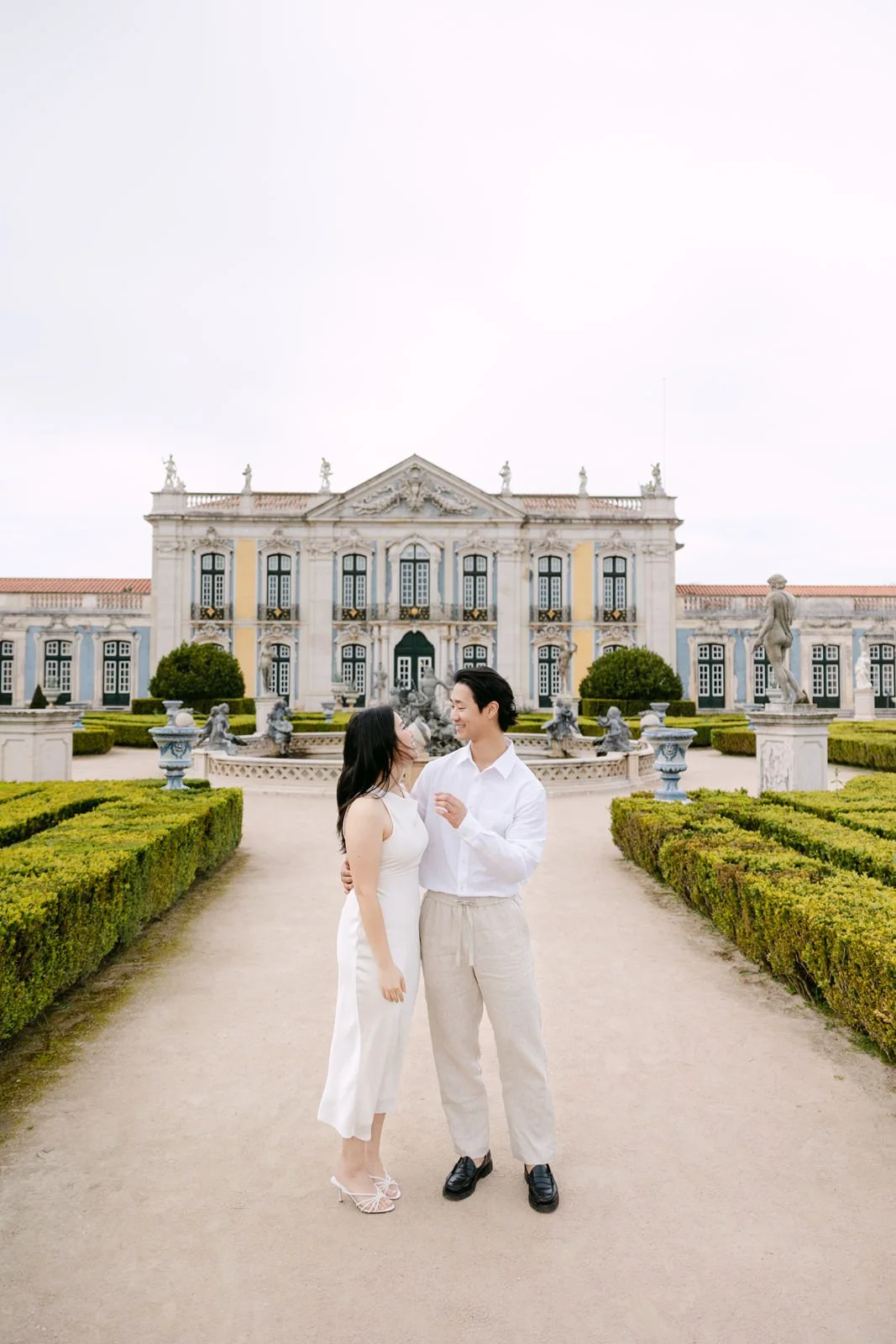 Couple walking through the formal gardens of Palácio de Queluz during their engagement photoshoot.