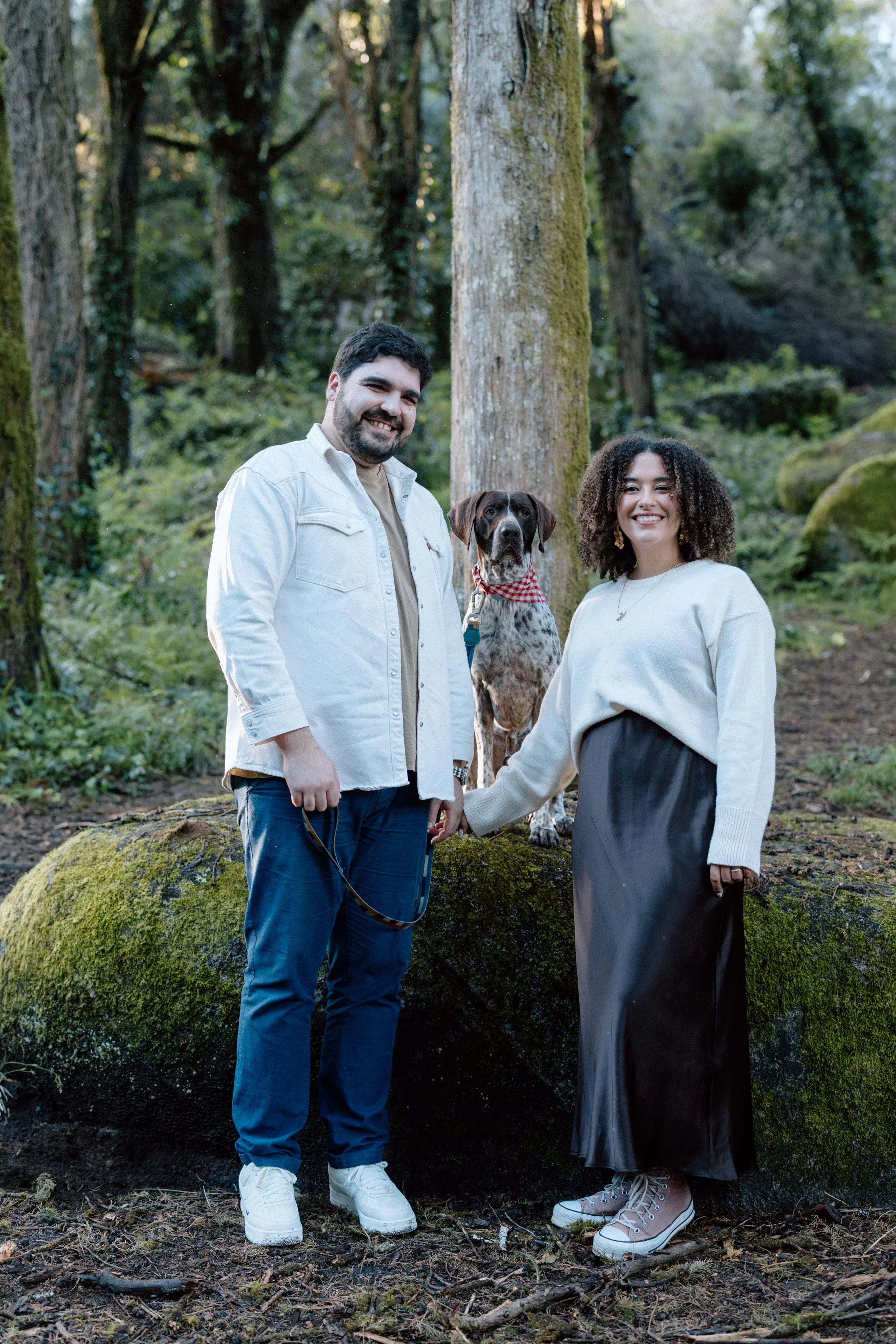 Couple posing with their dog during engagement photoshoot at Santuário da Peninha