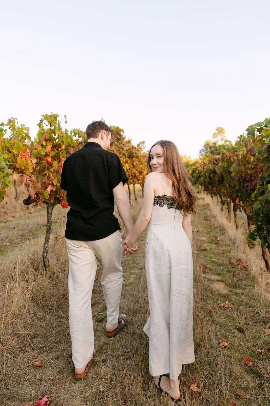 Newly engaged couple walking hand in hand through the vineyard at Quinta de Sant’Ana after their surprise proposal in Portugal.