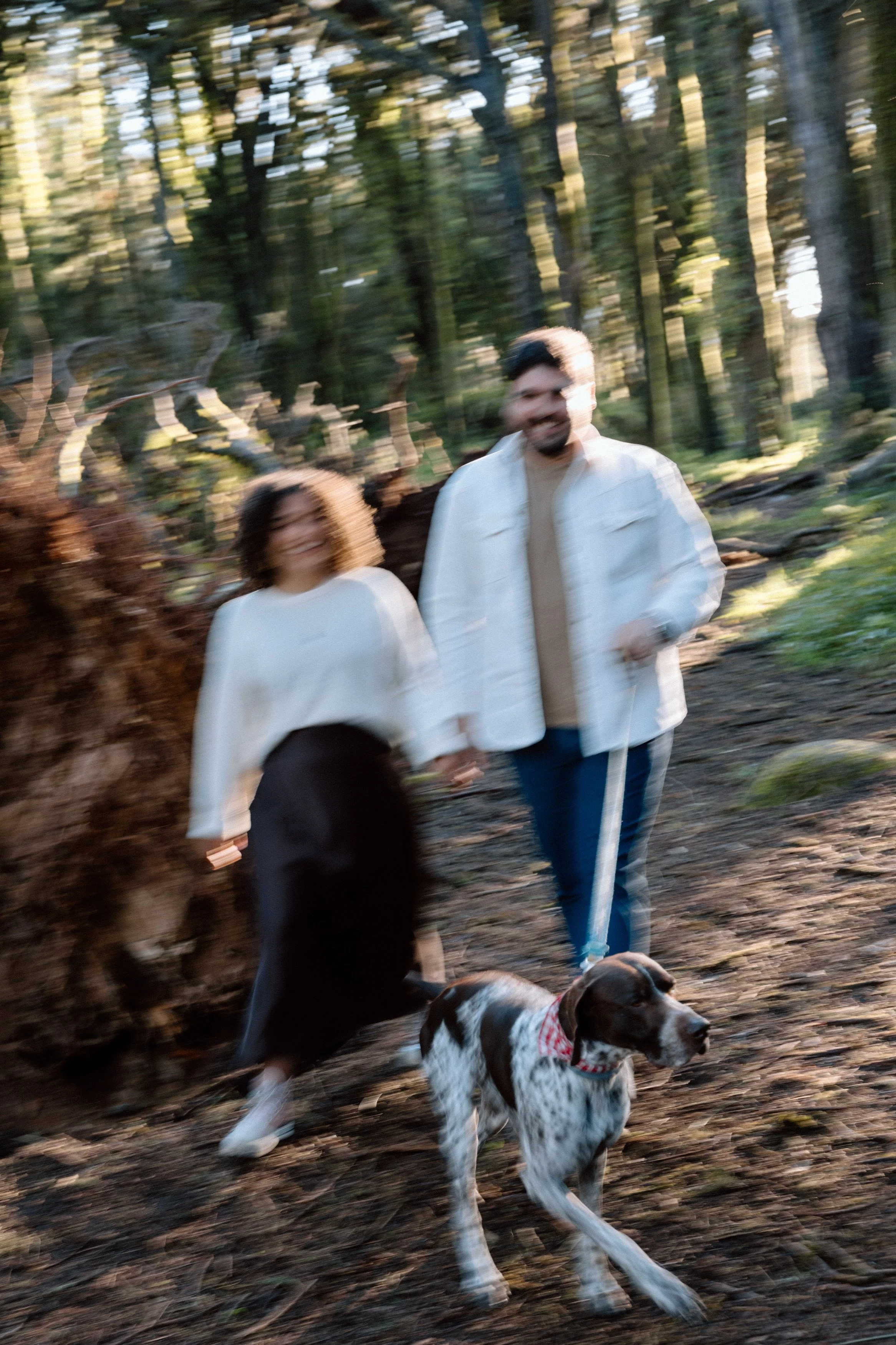 Couple walking their dog through forest during engagement session in Sintra
