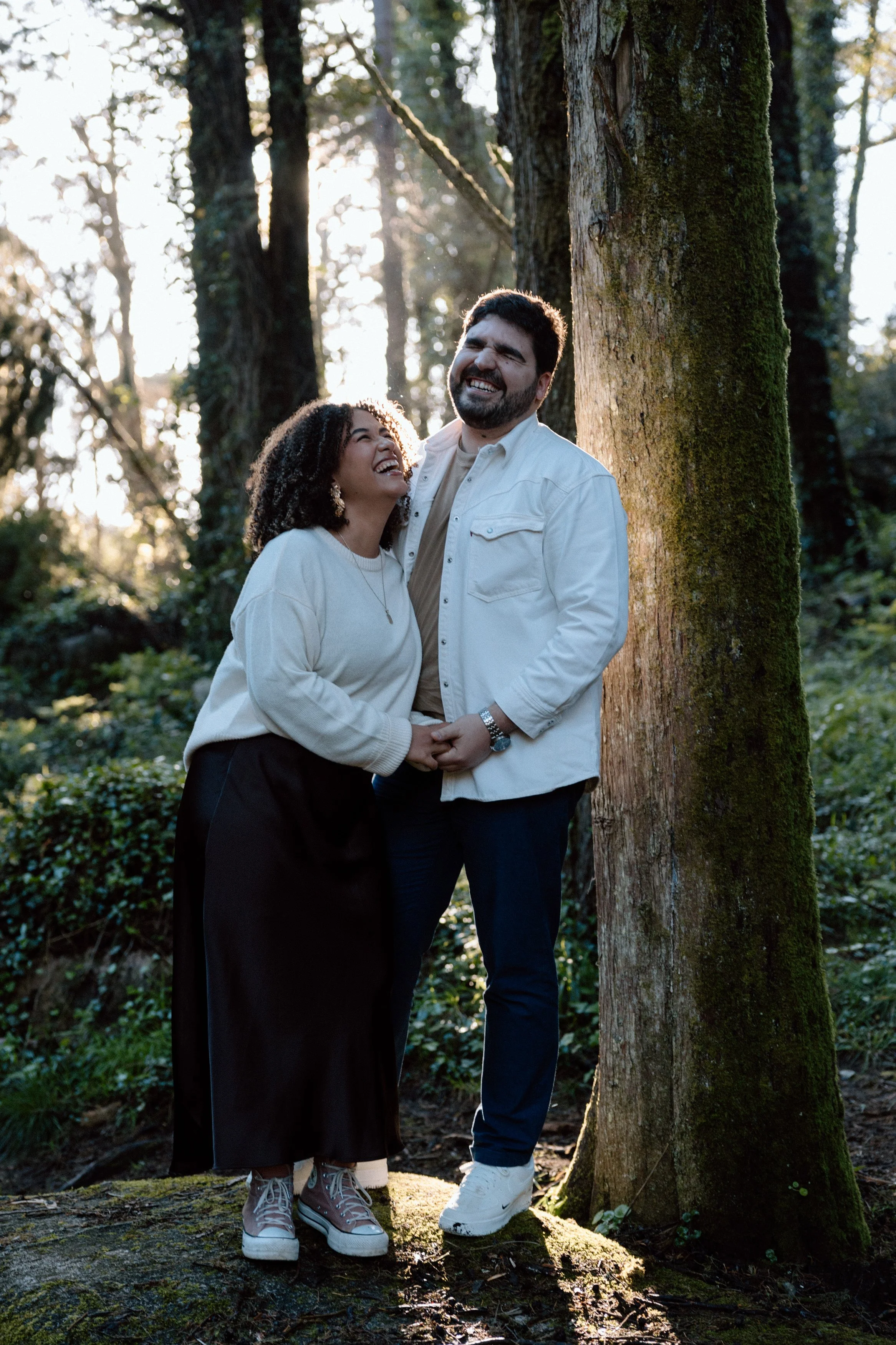 Couple laughing together in forest during engagement session at Santuário da Peninha in Sintra