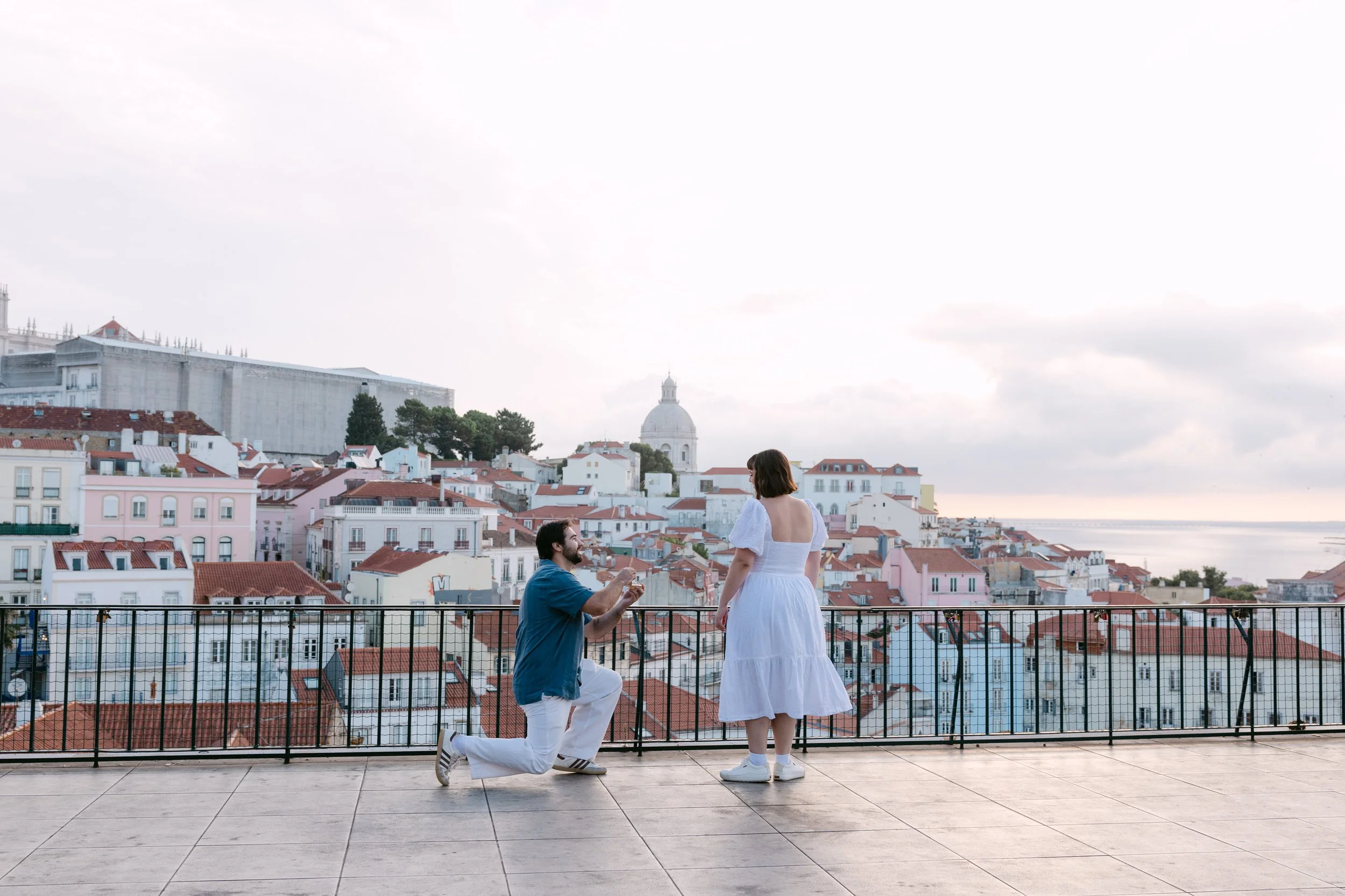 Abraham proposing to Emily at sunrise at Miradouro das Portas do Sol overlooking Alfama in Lisbon.