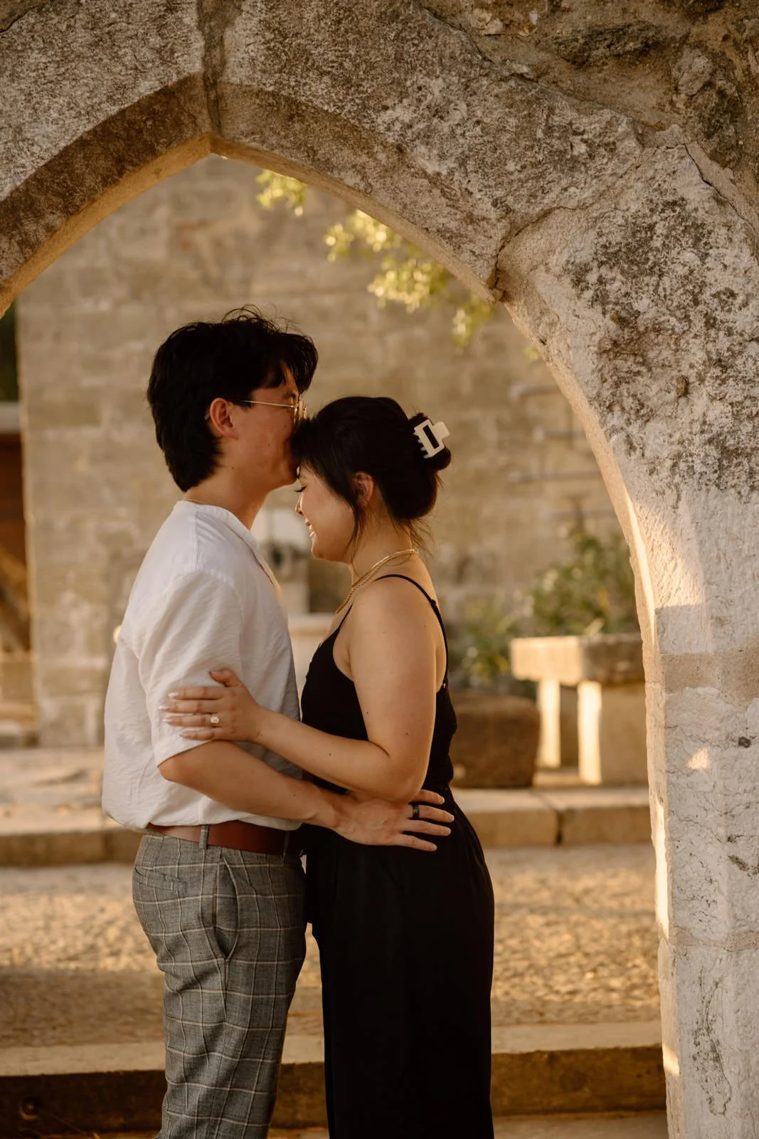 Newly engaged couple embracing beneath a historic stone arch at Castelo de São Jorge in Lisbon, Portugal.