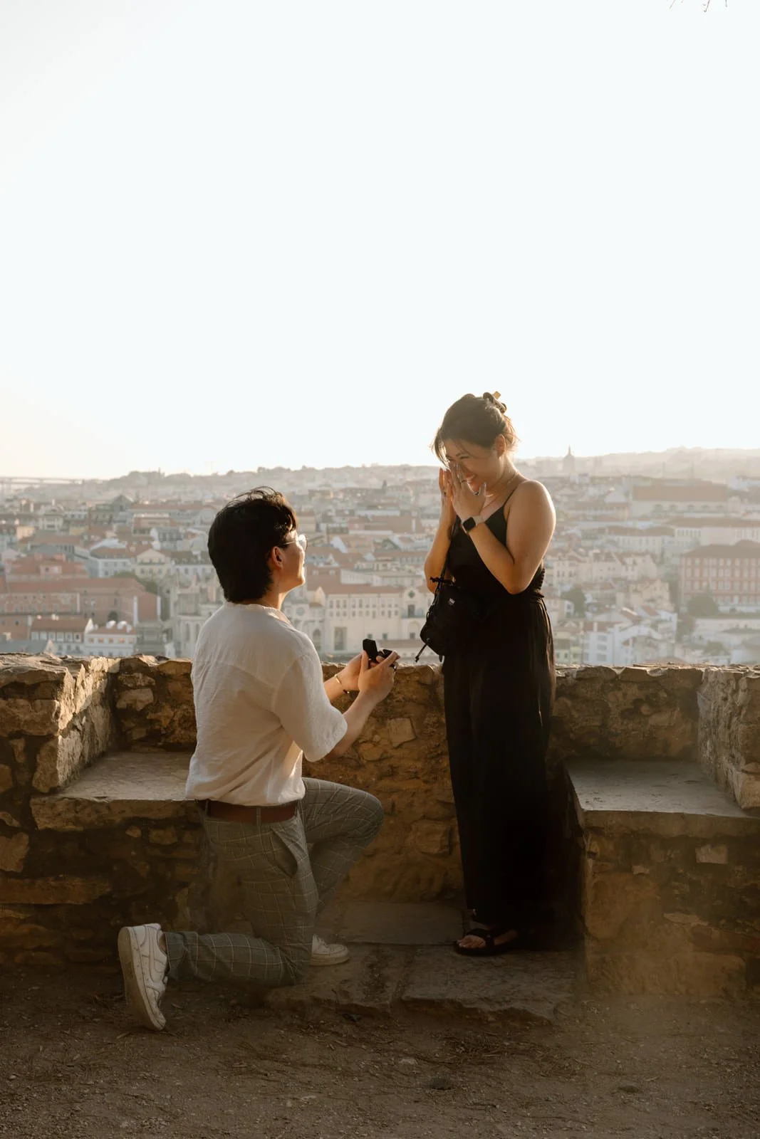 Couple celebrating a surprise proposal at Castelo de São Jorge with panoramic views over Lisbon.