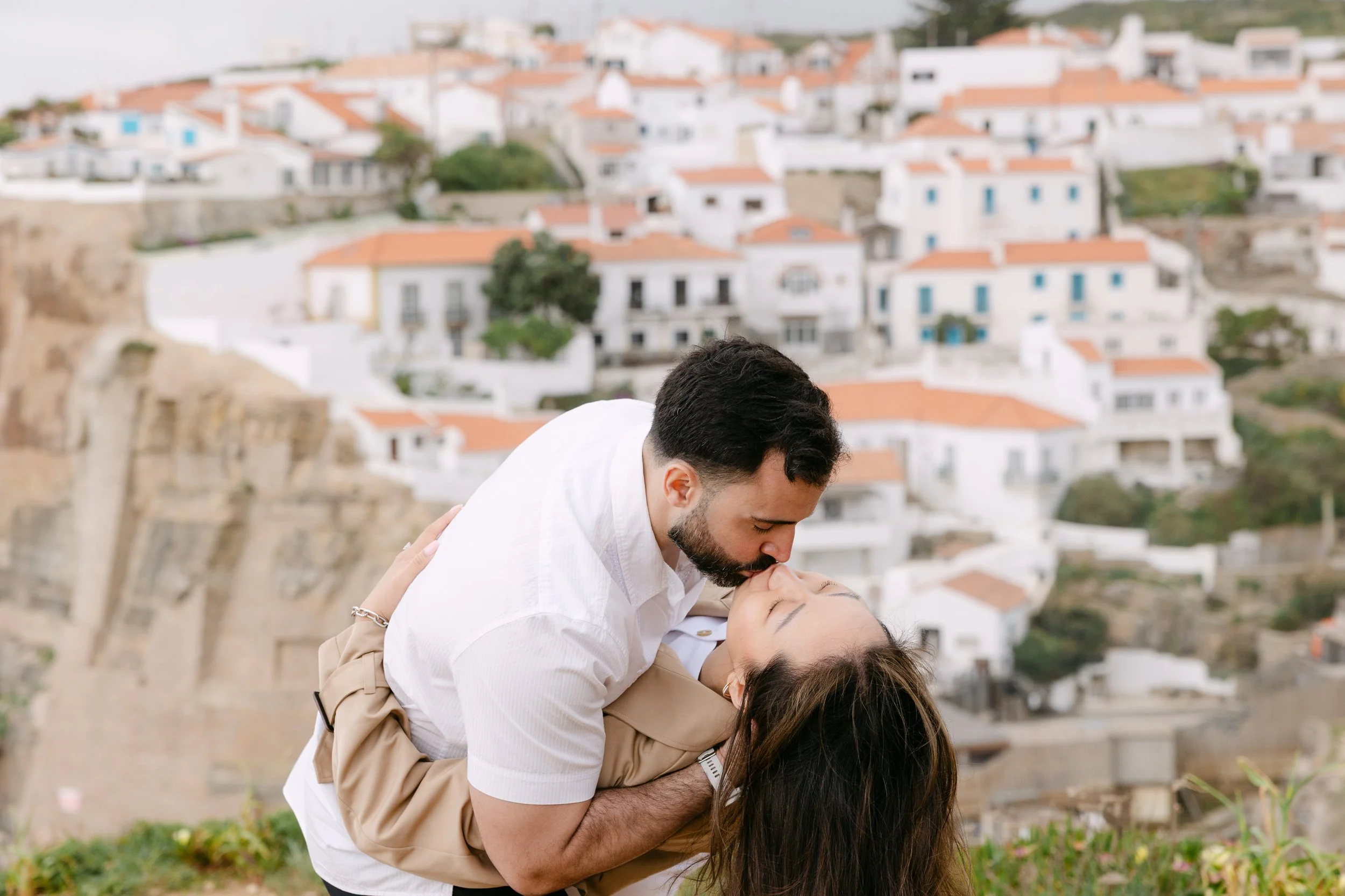 Couple kissing on the cliffs overlooking Azenhas do Mar during romantic Portugal photoshoot.