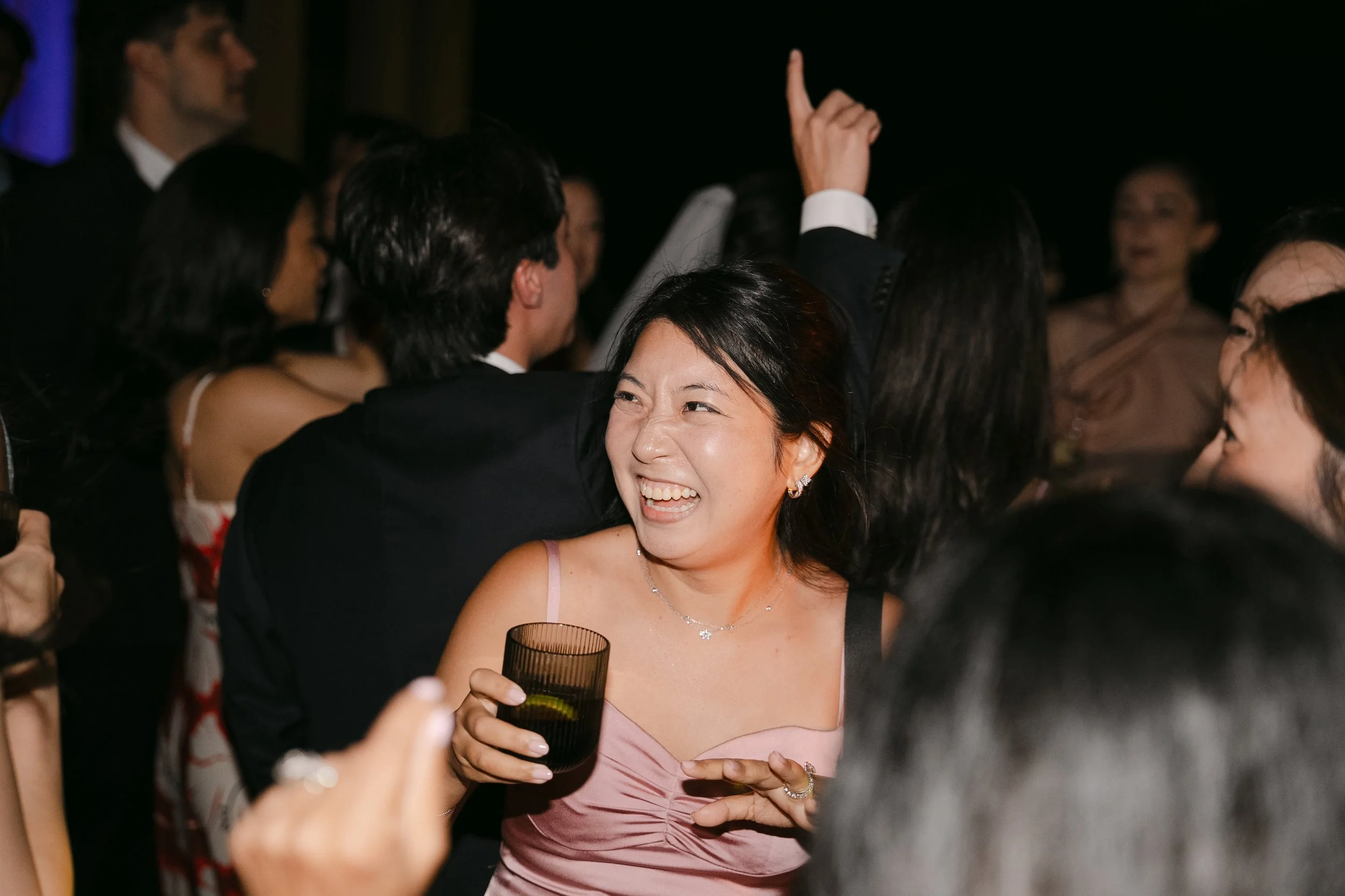 Wedding guest laughing with a drink in hand during the energetic evening party at Palácio Nacional de Queluz.