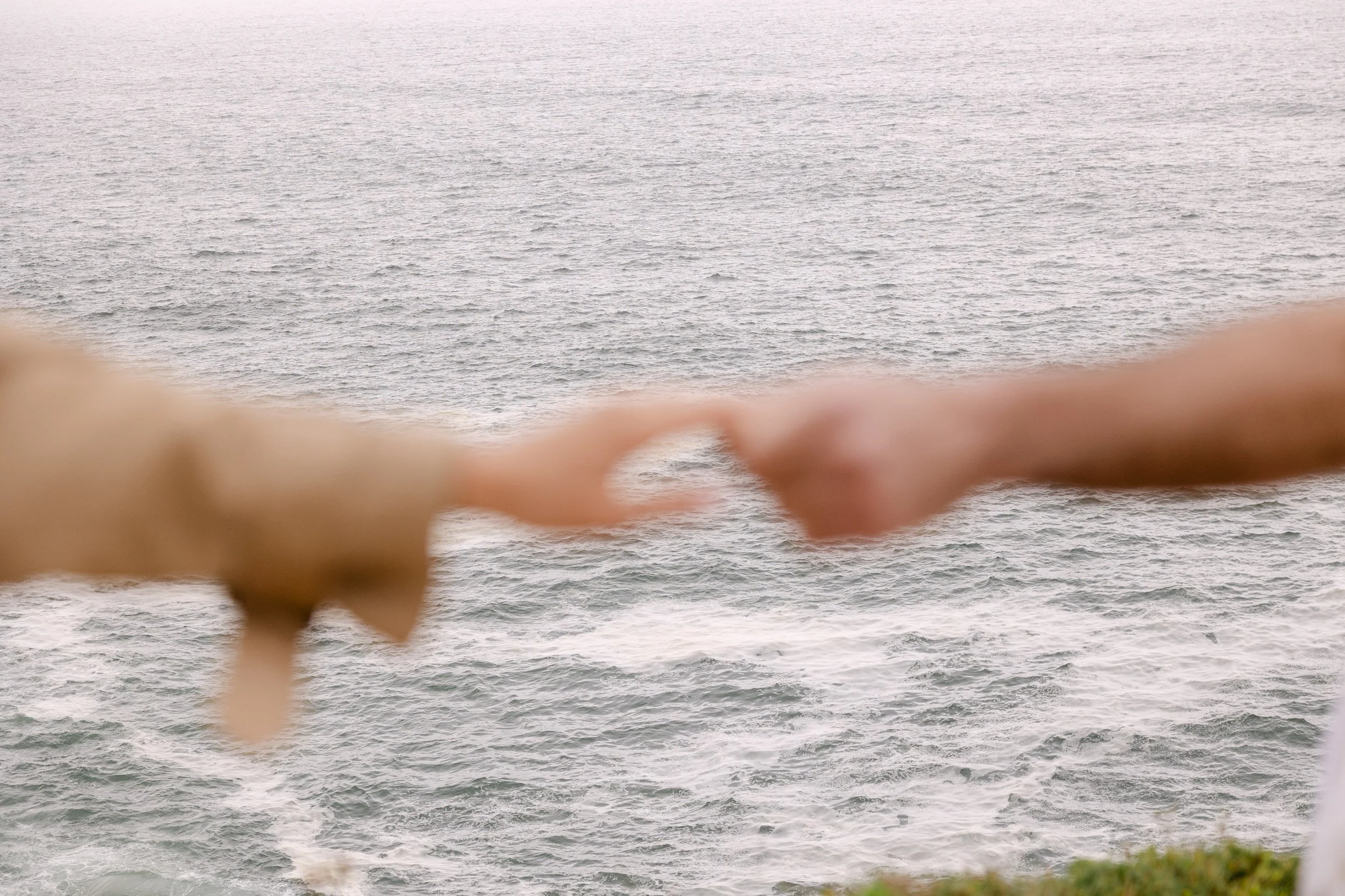 Engaged couple holding each other beside the Atlantic Ocean during romantic photoshoot in Portugal.