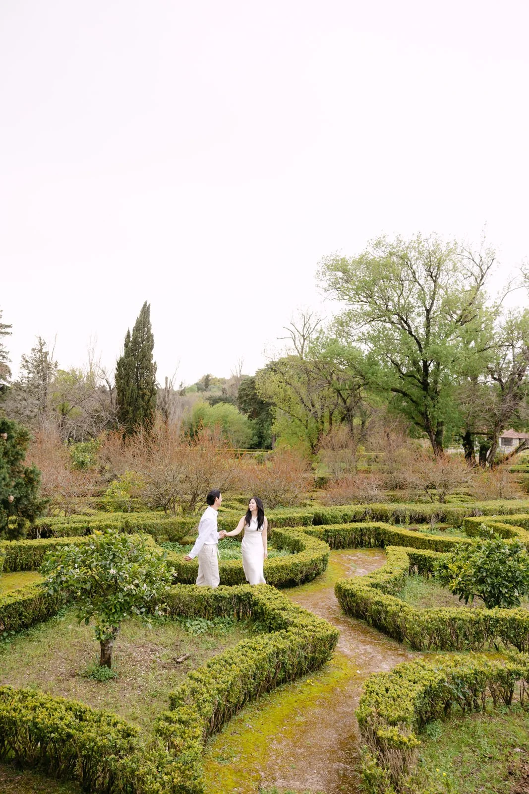 Couple exploring the geometric gardens of Palácio de Queluz during an engagement session.