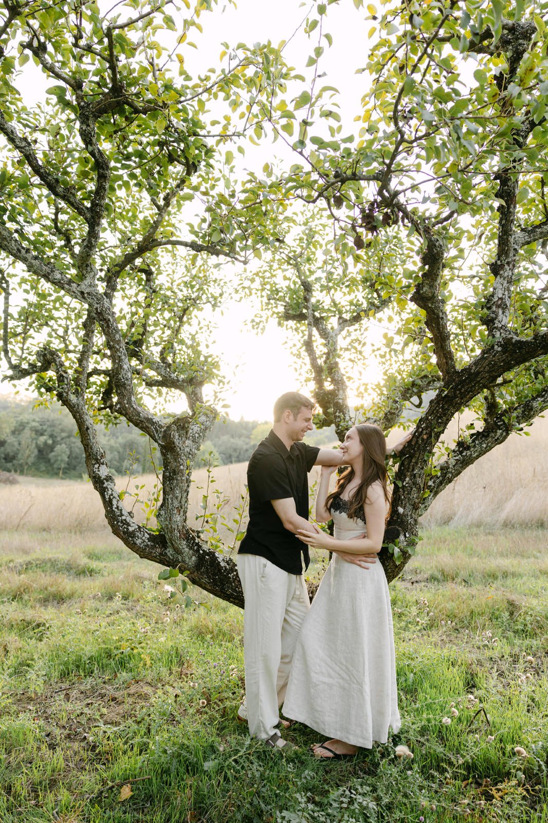 Couple sharing a quiet moment beneath a tree during their engagement photos at Quinta de Sant’Ana in Portugal.