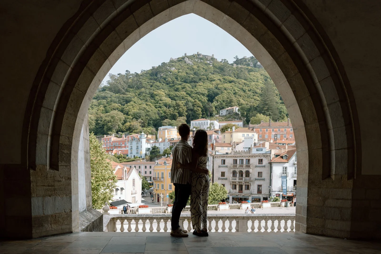 Engaged couple overlooking Sintra Village from the arches of Palácio Nacional de Sintra after a surprise proposal in Portugal.