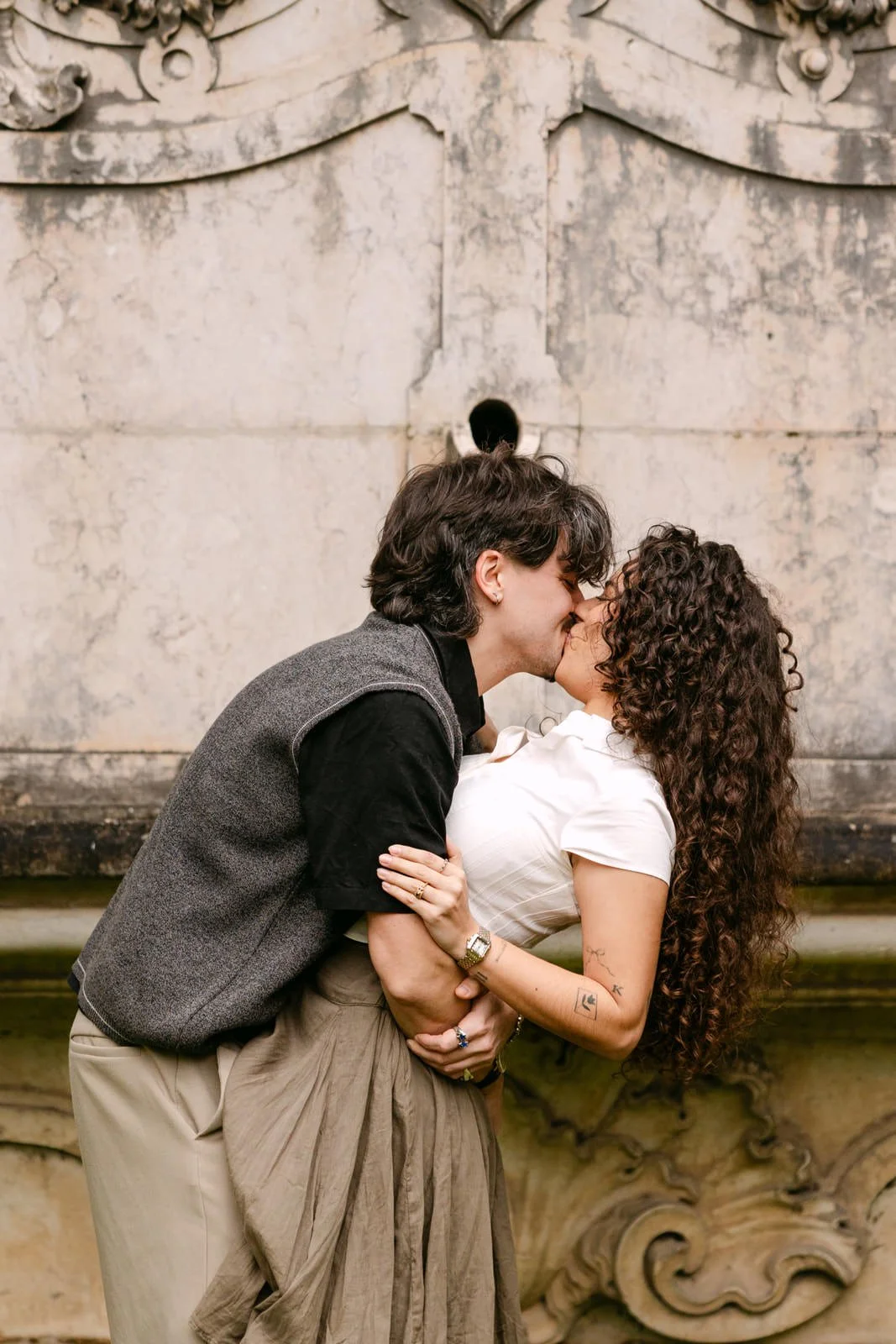 Couple kissing beside a historic fountain after a surprise proposal in Lisbon