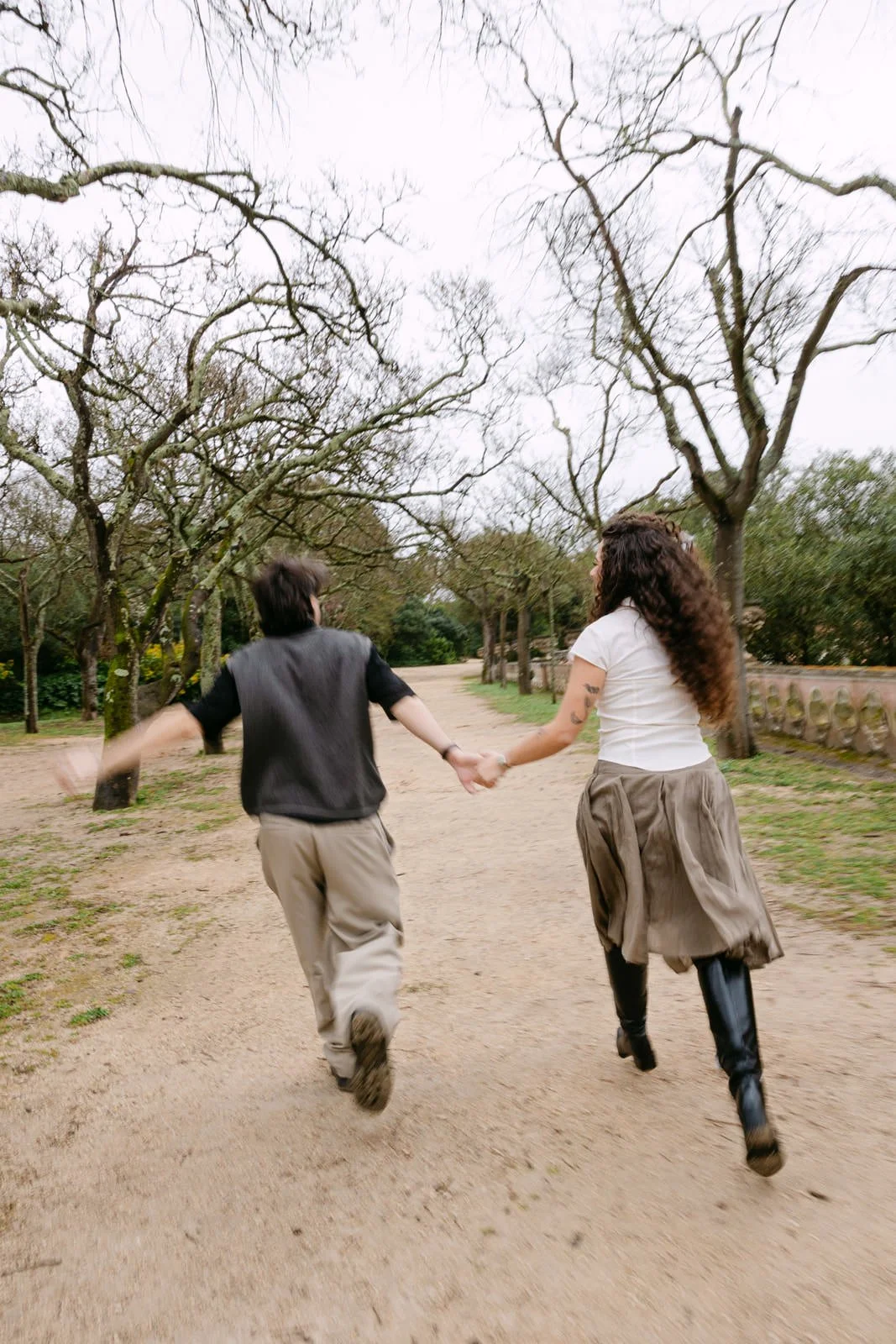 Engaged couple running hand in hand through Tapada das Necessidades gardens in Lisbon