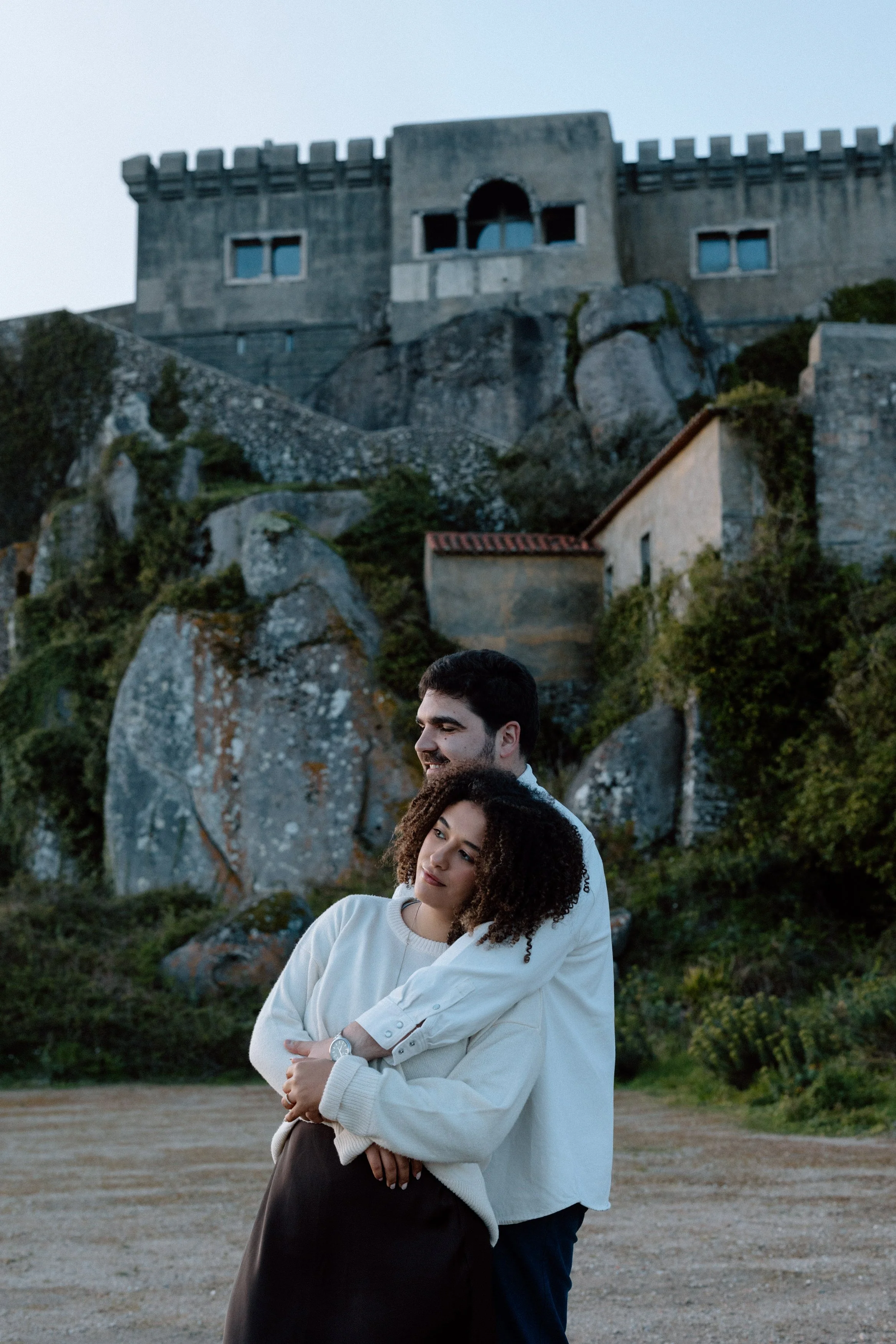 Couple embracing during romantic engagement photoshoot at Santuário da Peninha