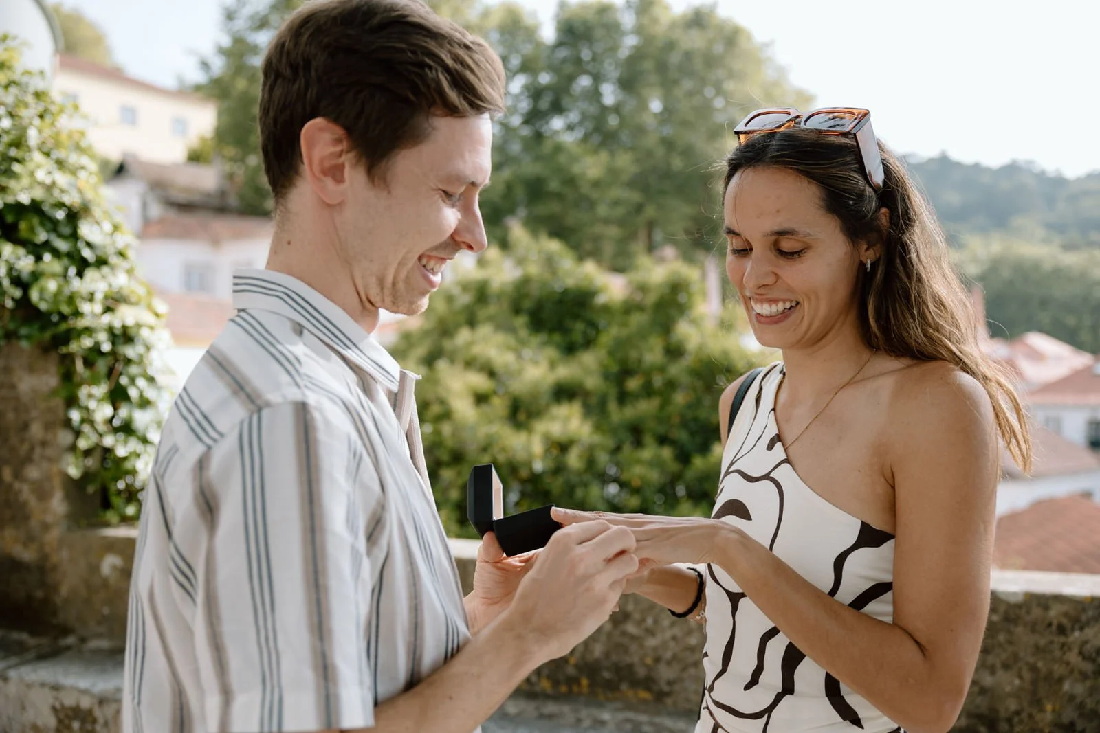 Justin placing the engagement ring on Carolina's finger during a surprise proposal in Sintra Village, Portugal.